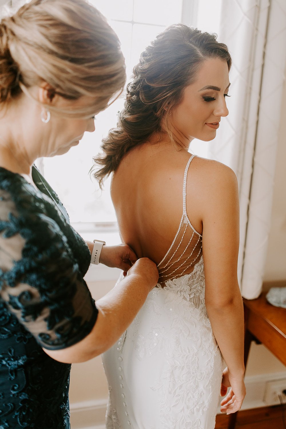 Bride has wedding dress zipped up while getting ready for wedding