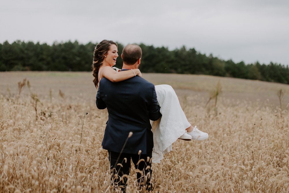 Groom carries bride through field at Lancaster, Pennsylvania wedding