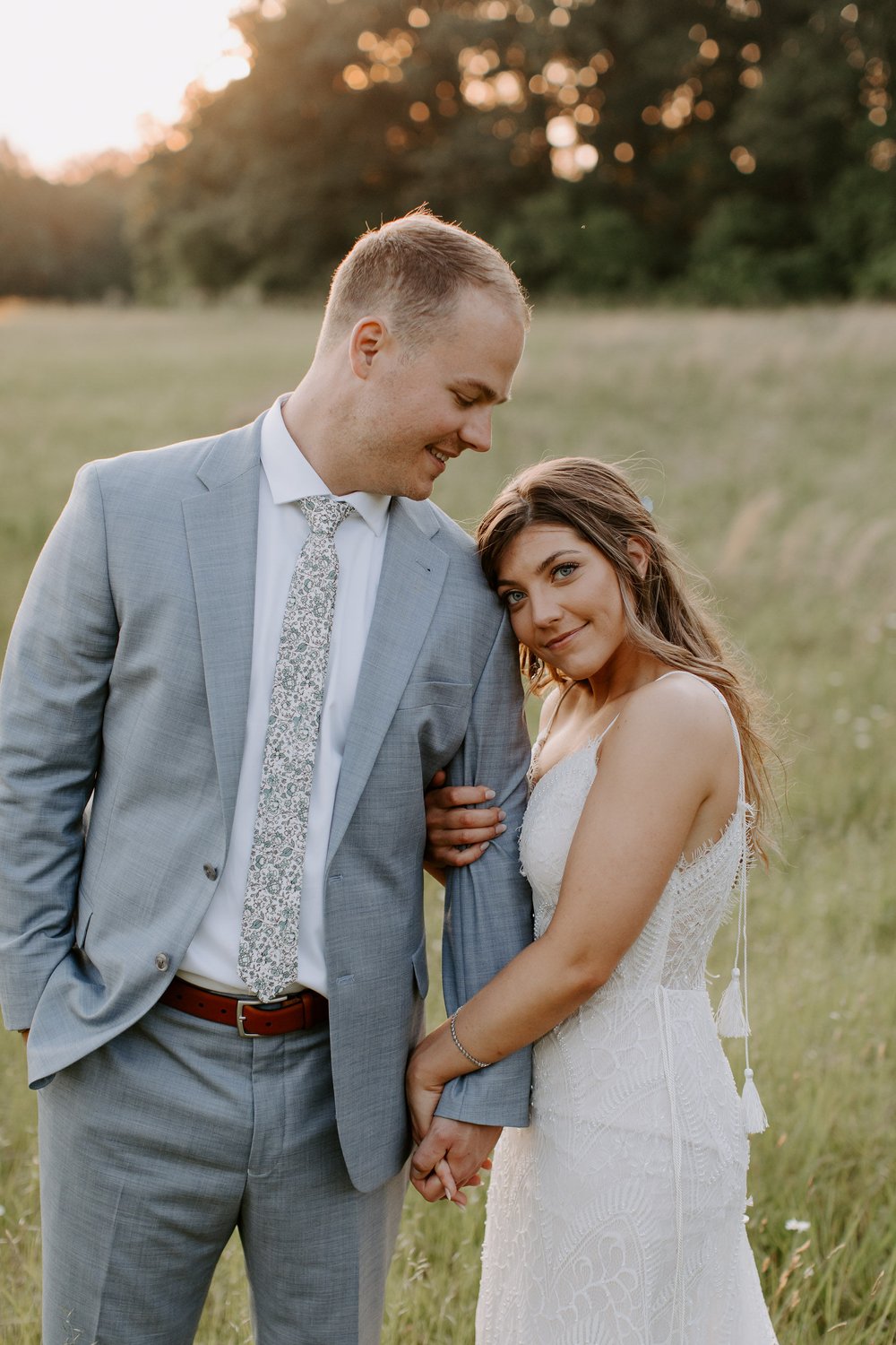 Couple embraces in wedding field sunset photos