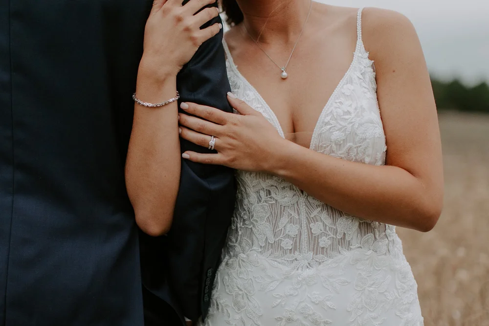 Couple embraces with the bride holding the groom's arm