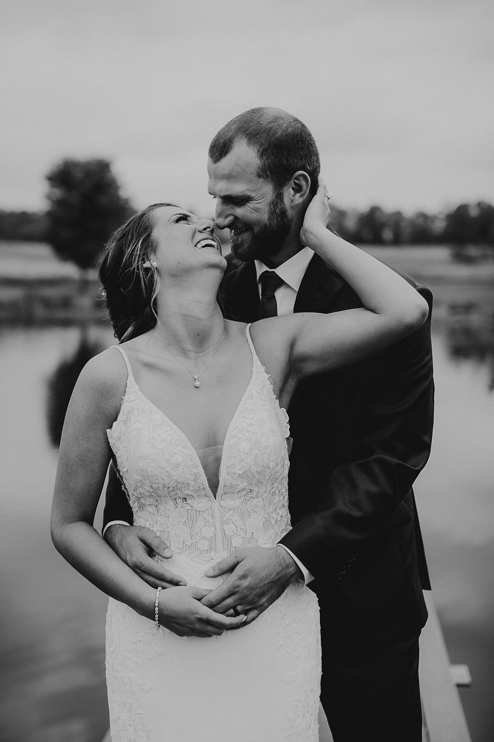 Groom holds bride while she leans back on him laughing