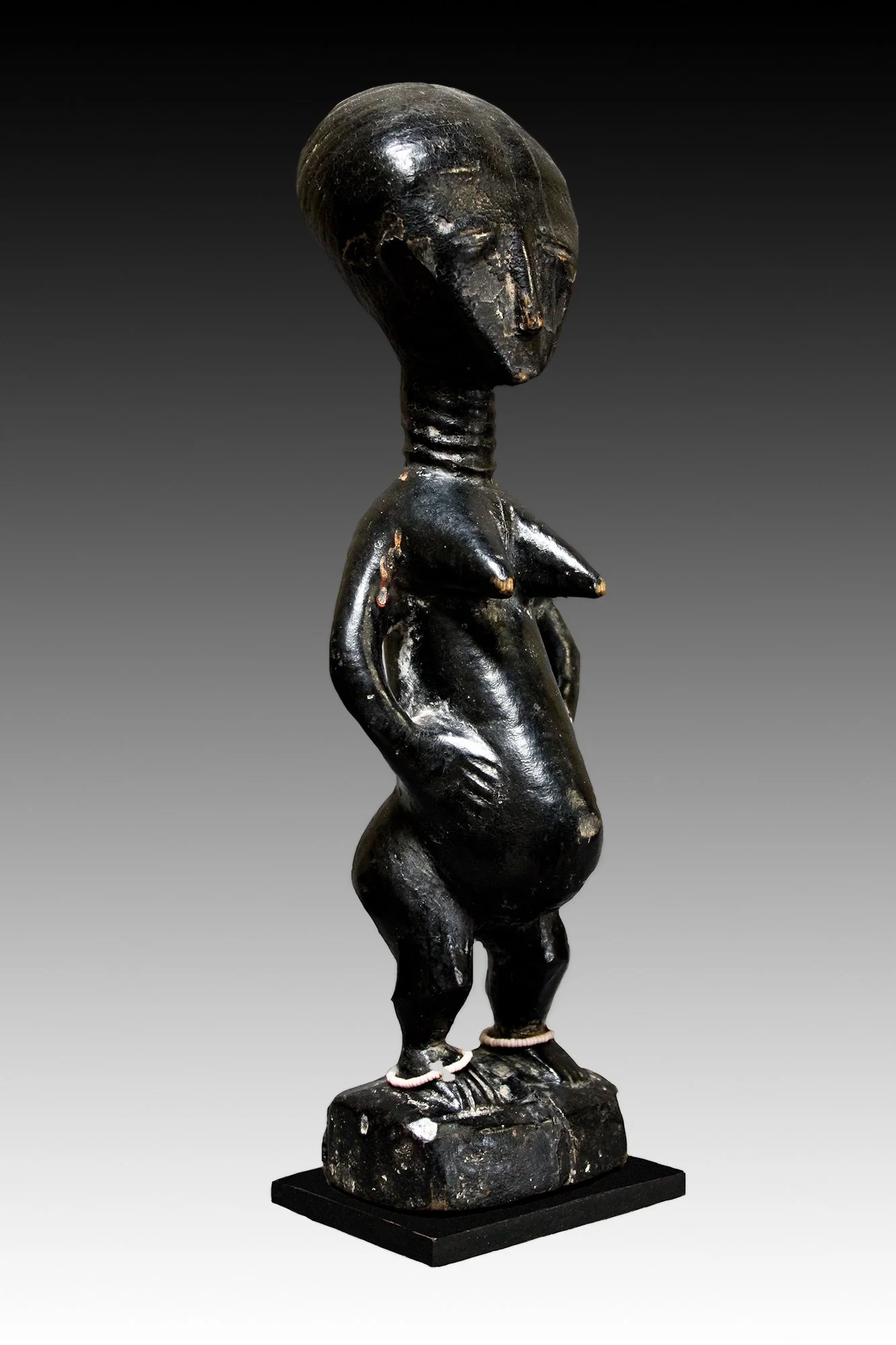 Akan figure has a glossy black patina with a domed head, ringed neck, pointy breasts and has beaded anklets and bracelet.  www.intriguegallery.com