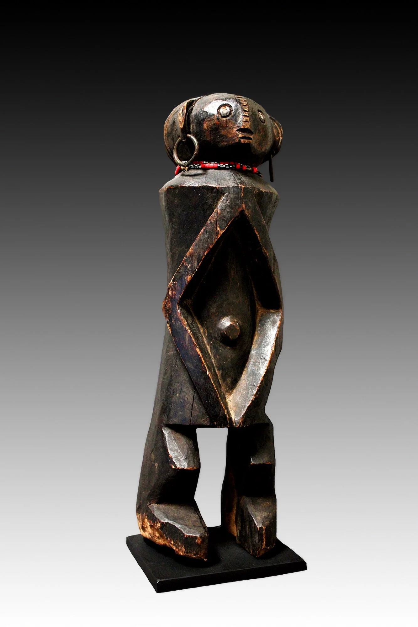 Banda figure's head is ovoid shaped with shell eyes, scarification from the forehead to nose, metal rings in the ears and wears a glass beaded necklace.  www.gallerytribalart.com