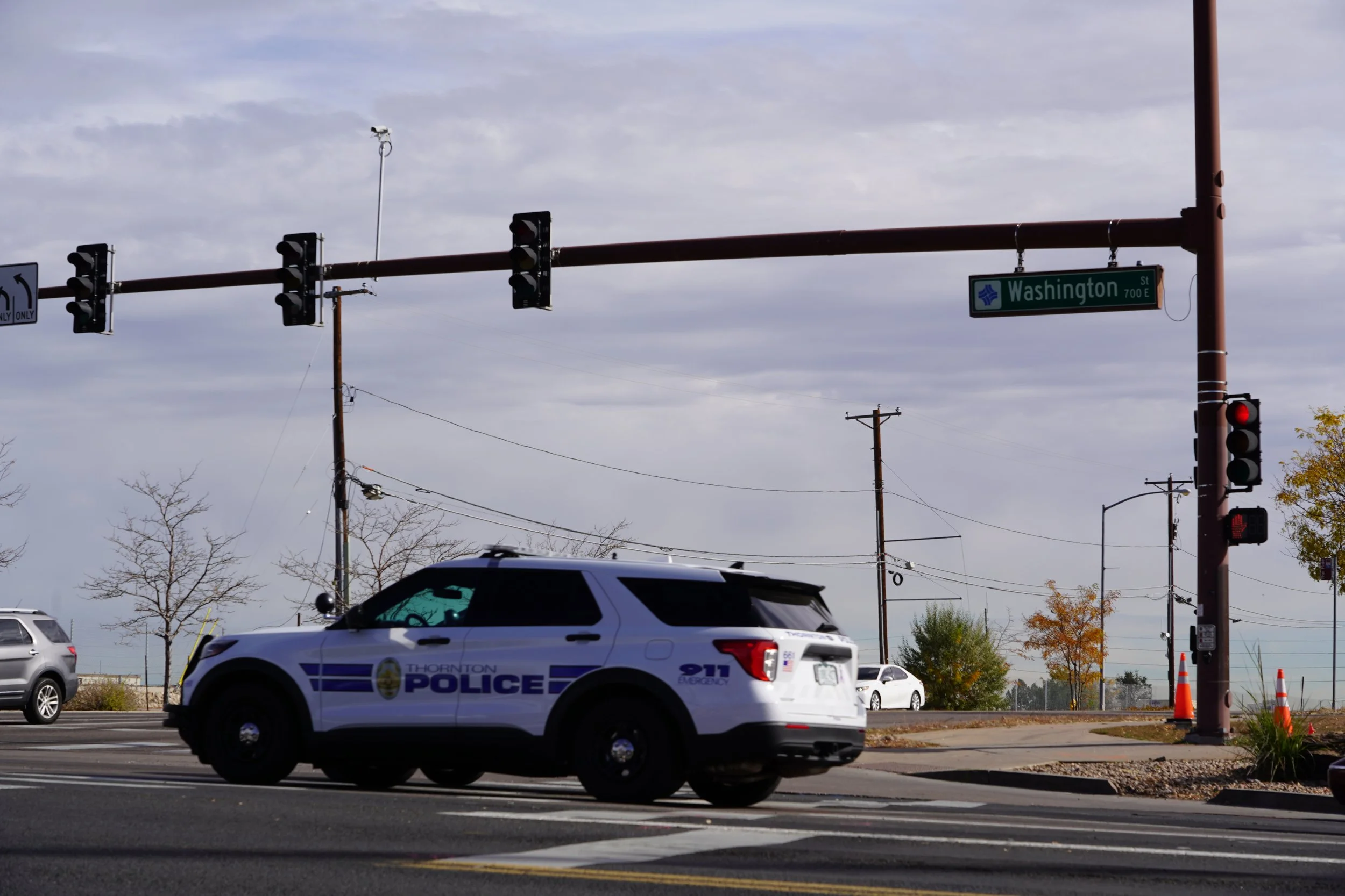 Thornton Police car driving through the intersection of 88th and Washington, showing the traffic signal and one traffic operation camera.