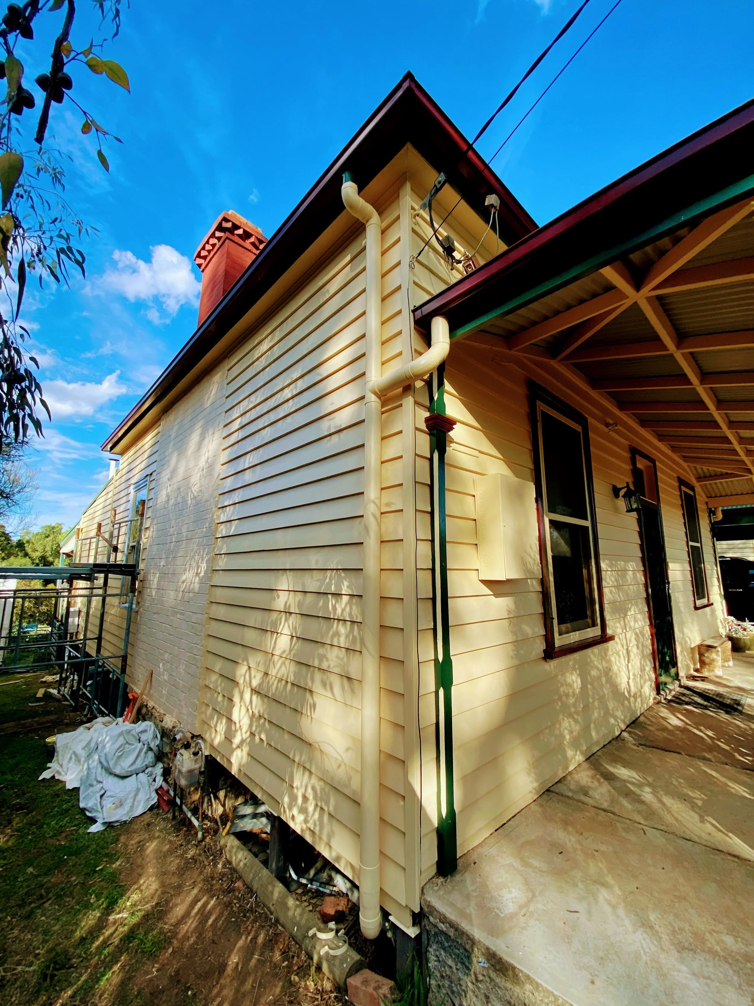 Sunlit weatherboard home showing newly painted porch, trims, and restored timber surfaces.