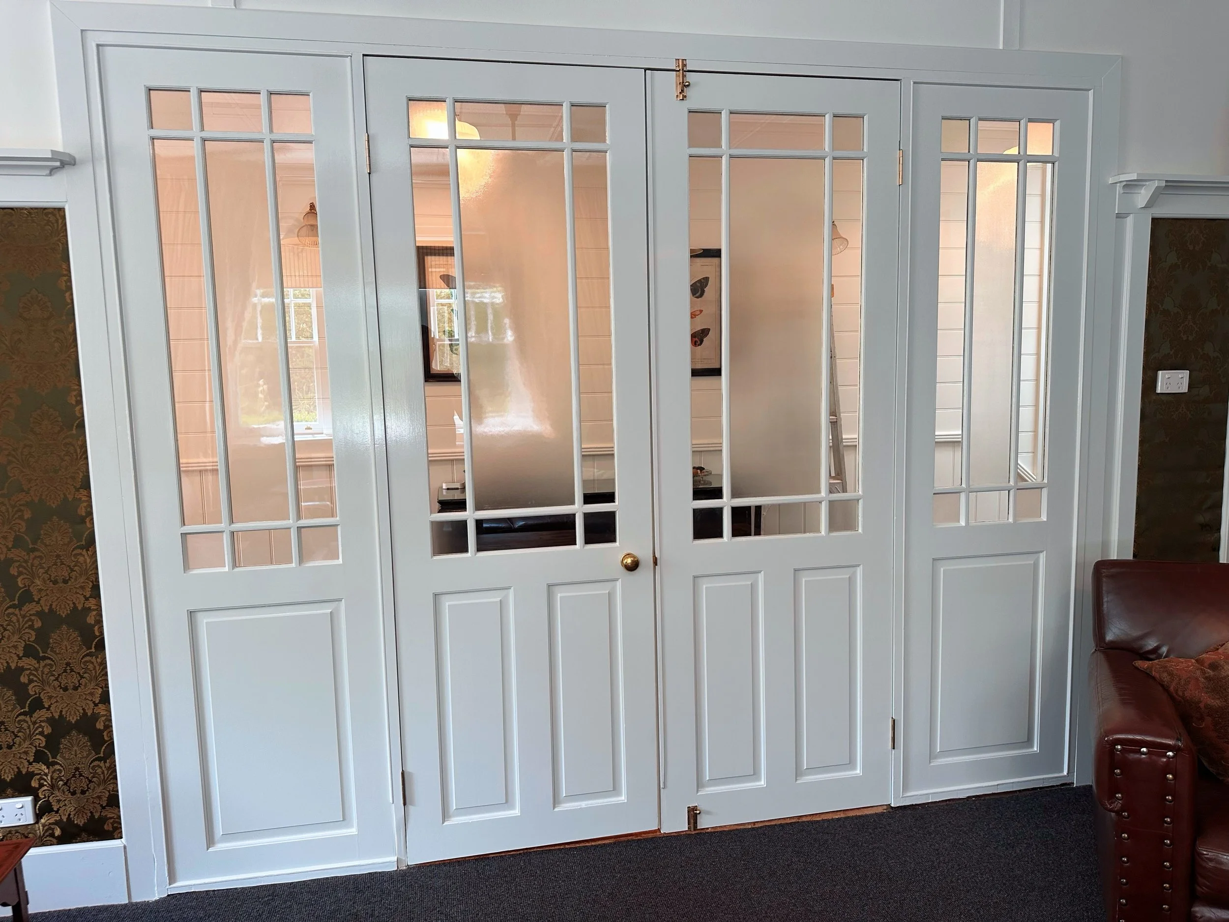 A white folding room French door with glass panes in a living room, partially separating the space.