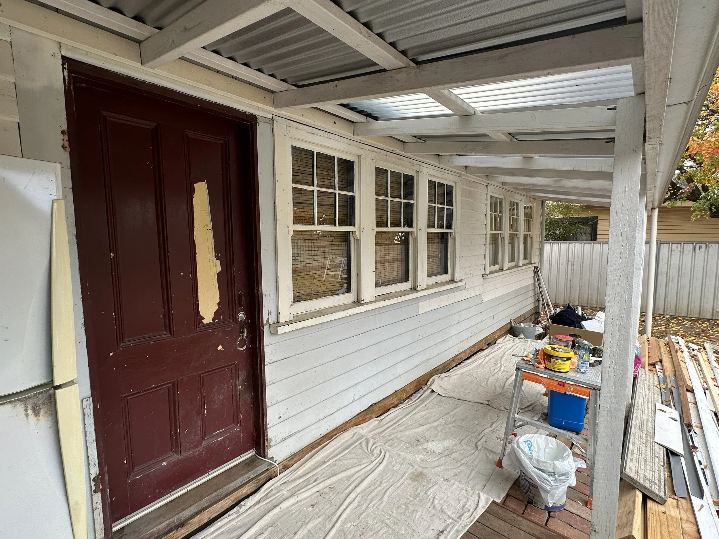 Before photo of back porch with weathered timber and peeling exterior paint.