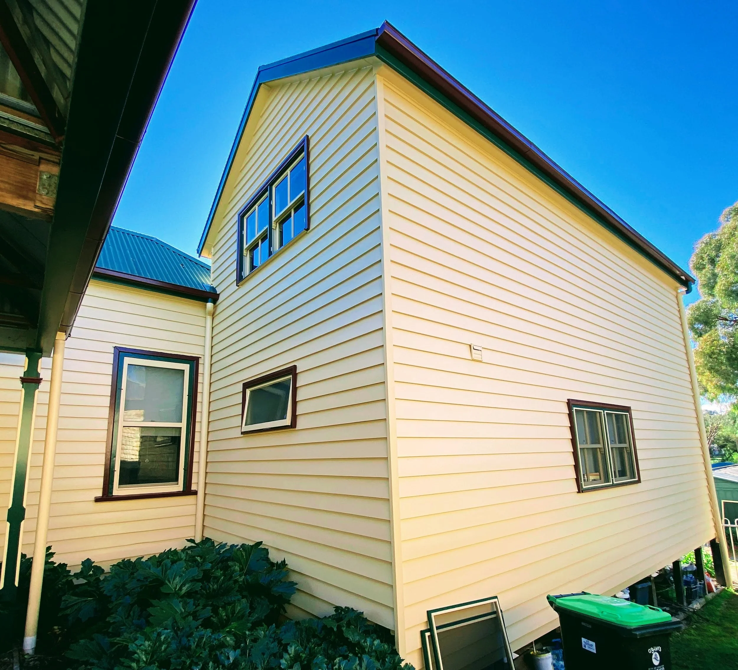 Double‑storey weatherboard repaint with repaired boards and uniform finish along the side elevation
