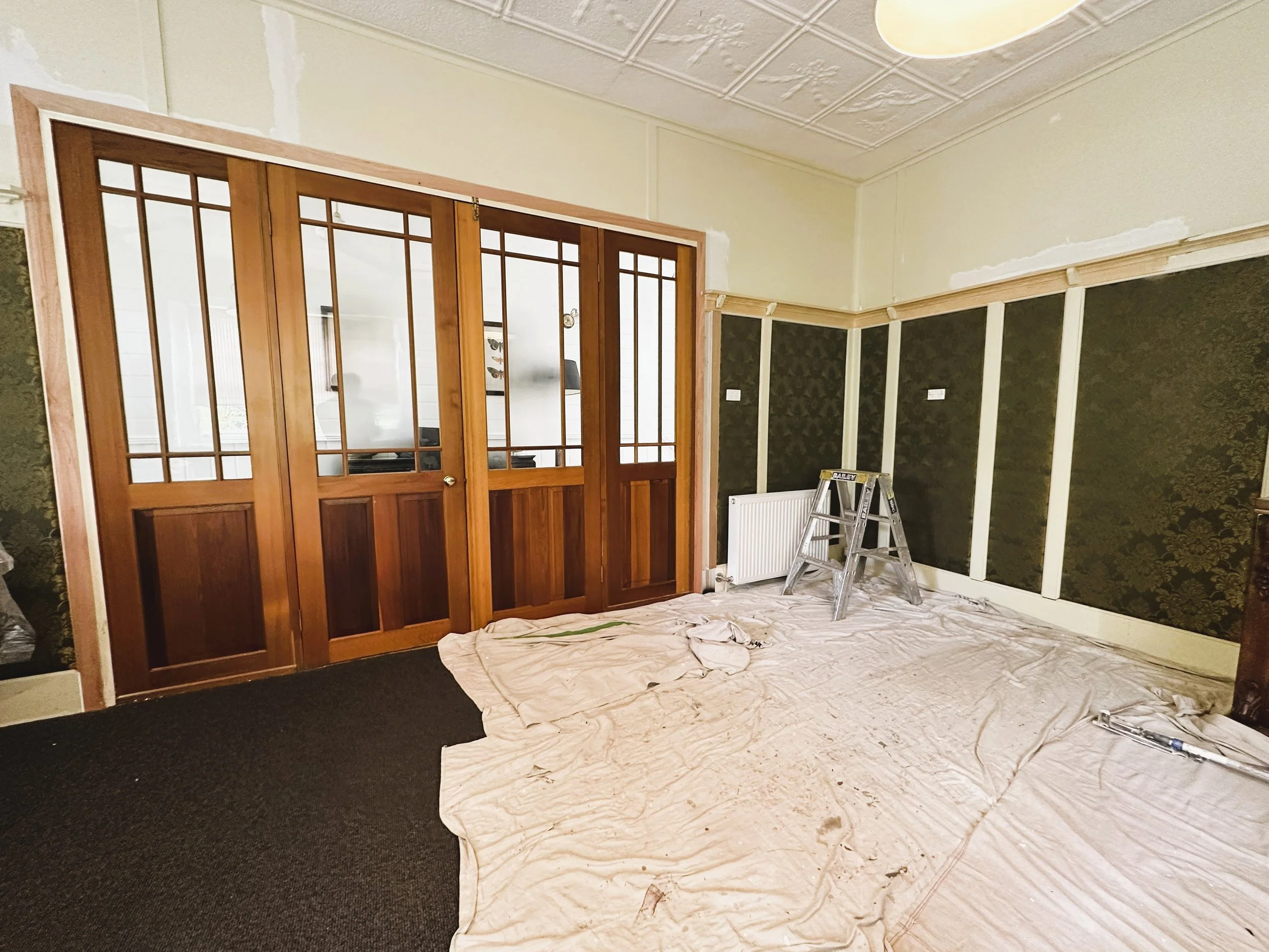 Before photo of parlour room timber trims showing worn varnish and surface damage.