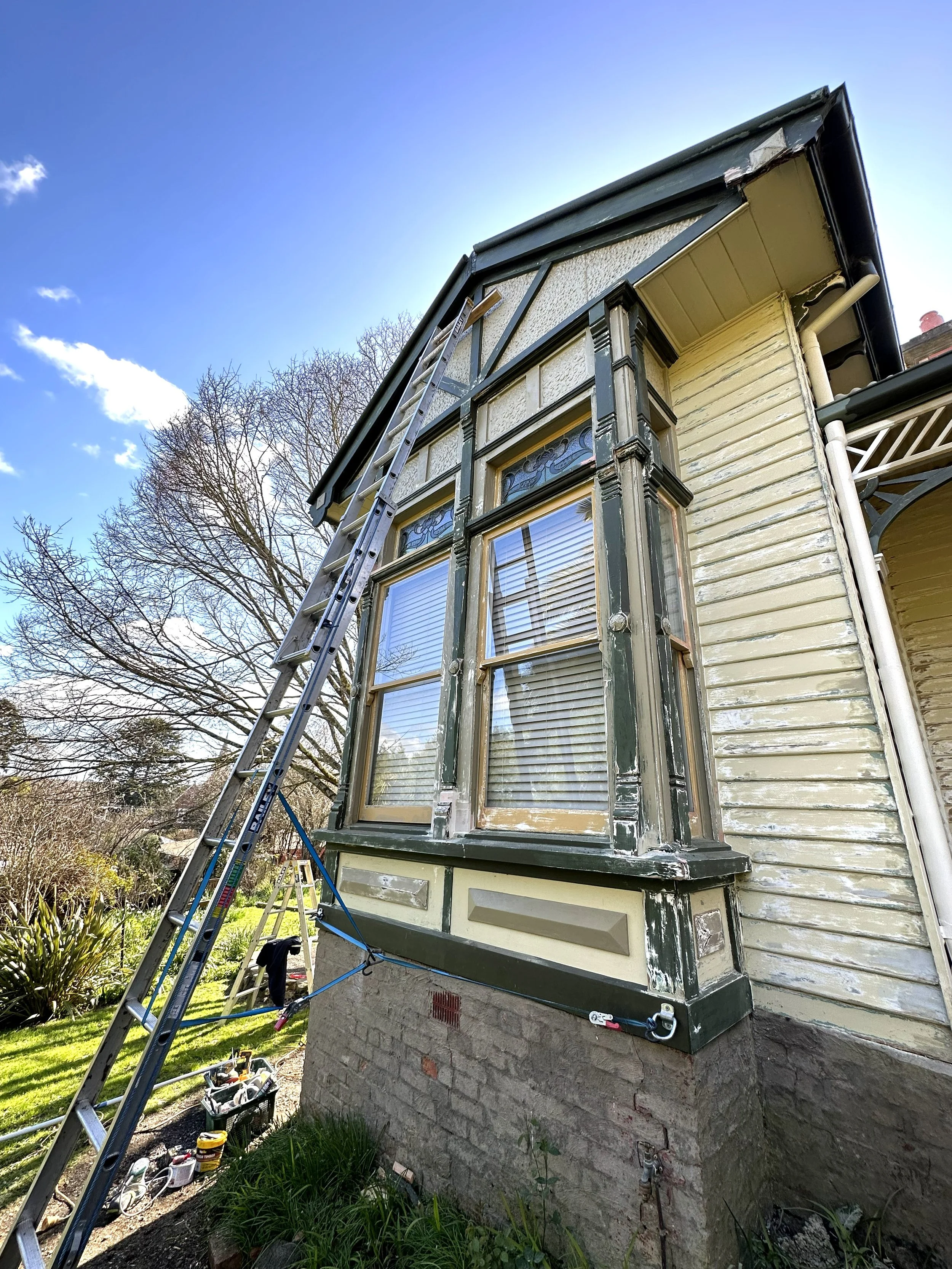 Before photo of exterior façade with faded paint and visible timber deterioration.