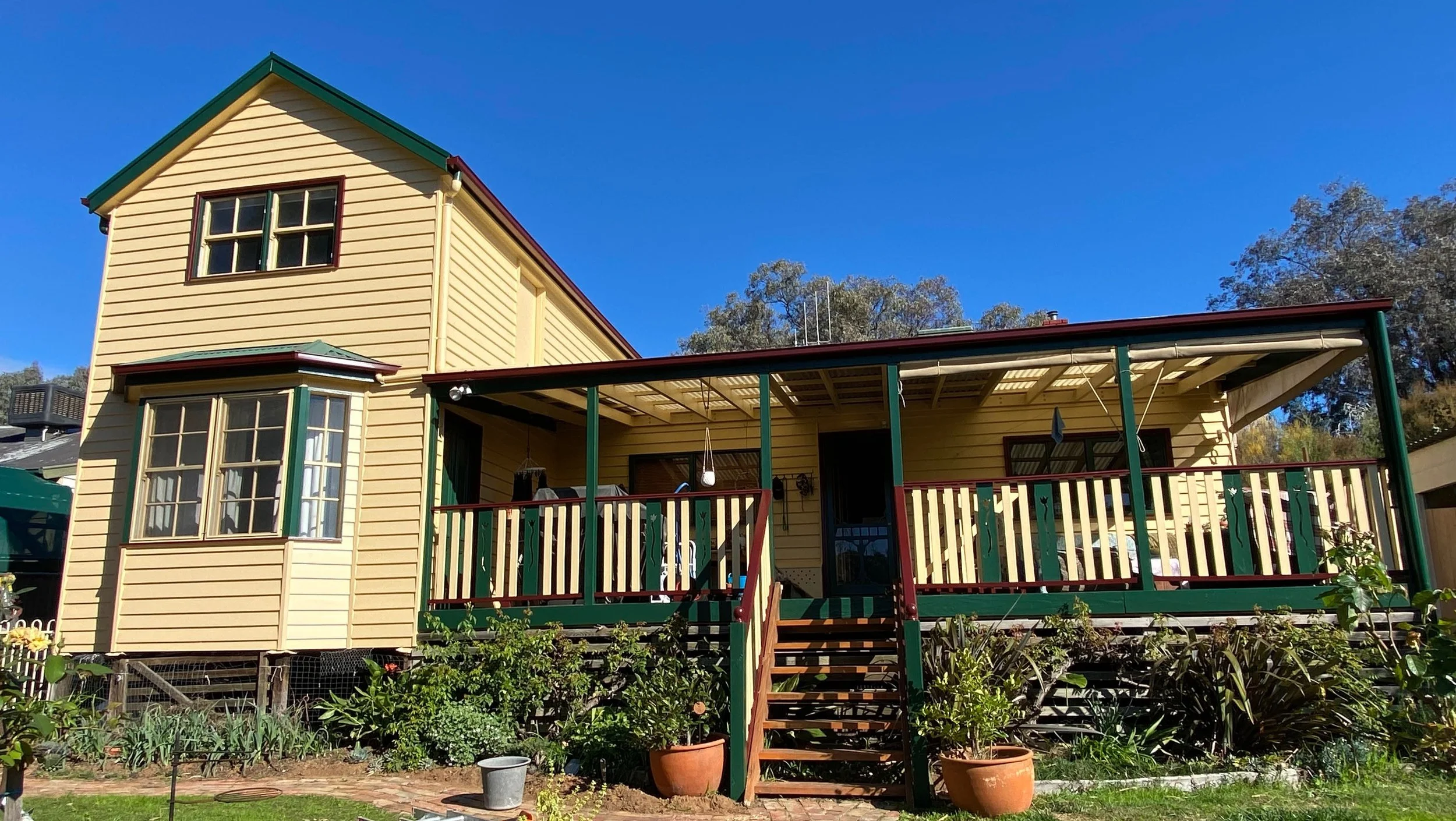 Sunlit weatherboard home showing newly painted porch, trims, and restored timber surfaces.