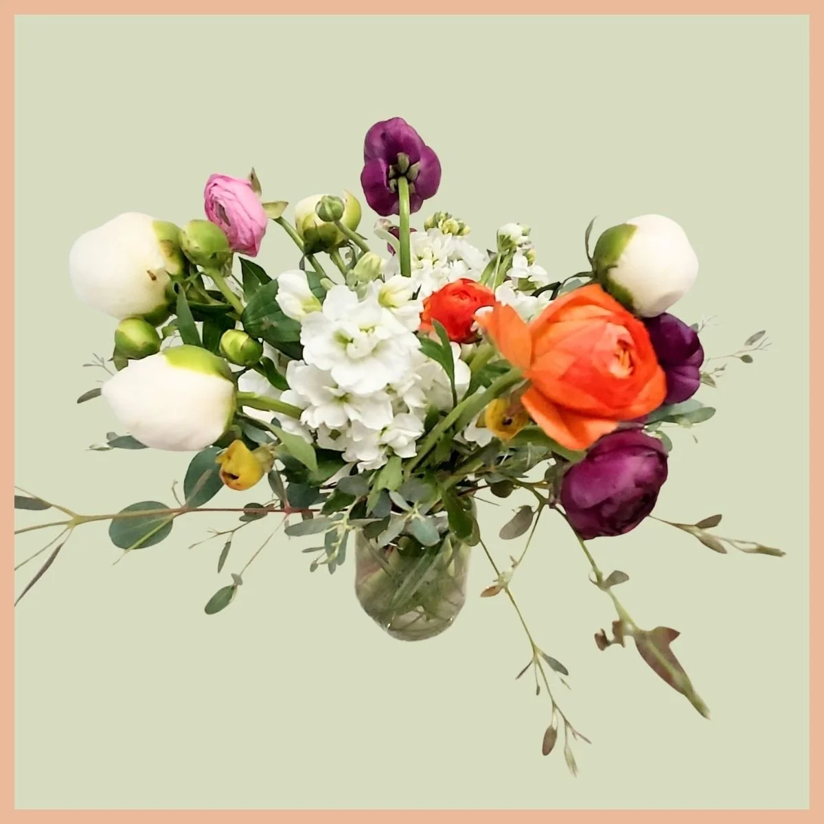 a vase of loose shaped drooping white, pink, and orange ranunculus flowers