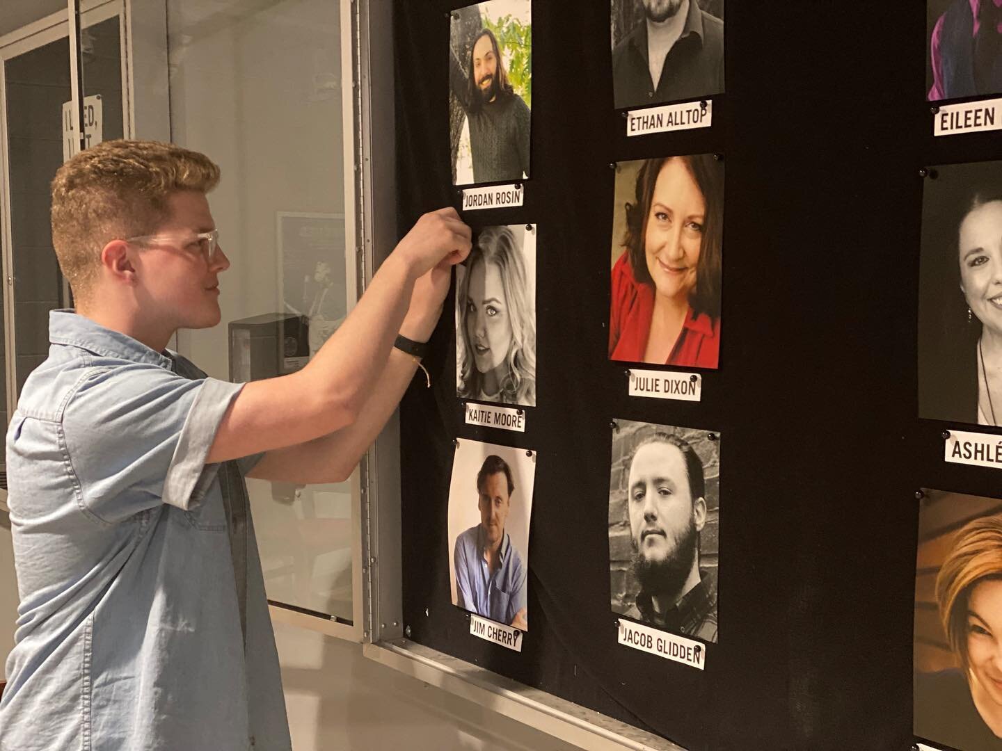 Will is hanging headshots of our cast members in the lobby to prepare for our in-person viewings of our shows! Check out the full displays in the New Theater!