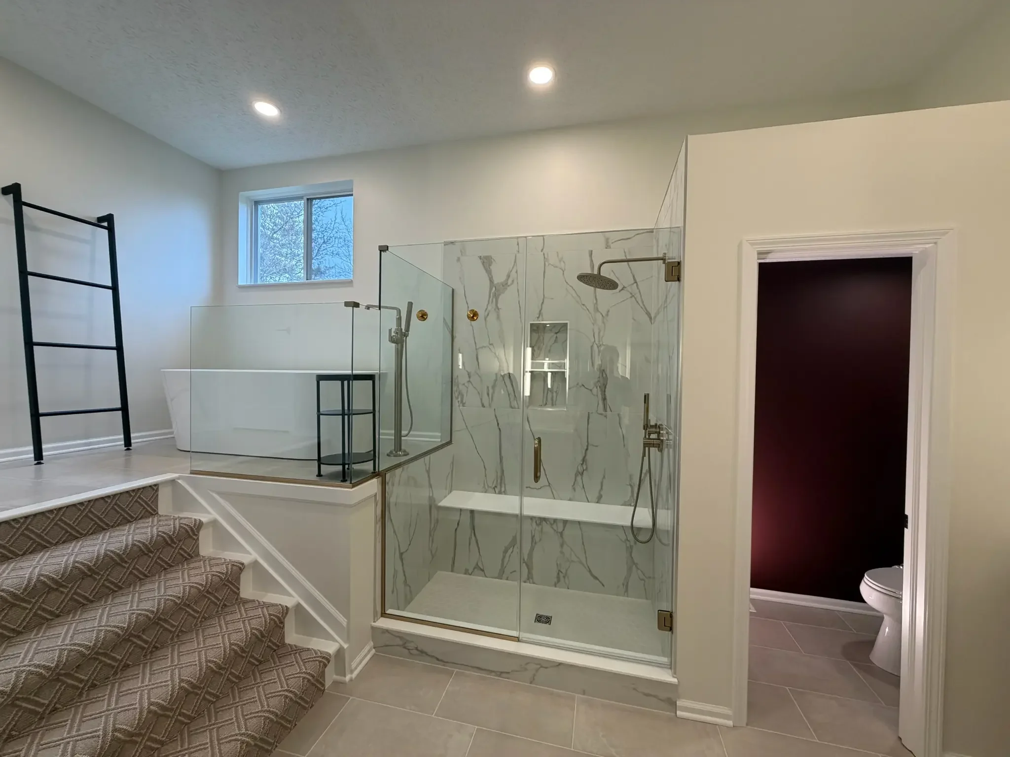 Dublin Ohio primary bath remodel with soaking tub platform, glass surround, and marble-look walk-in shower with brass hardware