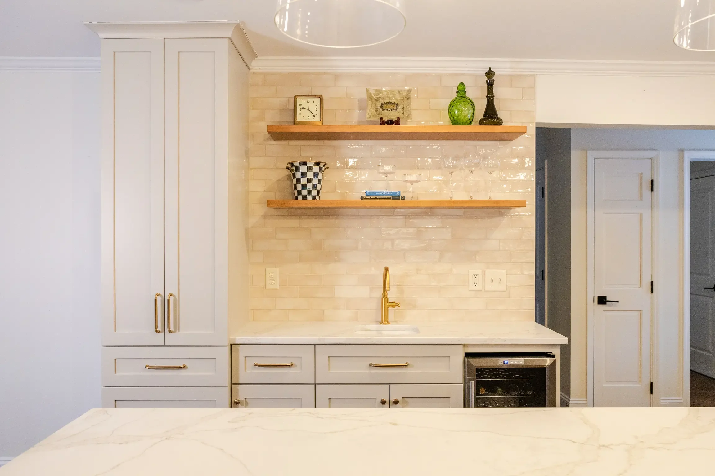 Custom kitchen and bar remodel in Columbus, Ohio featuring built-in cabinetry, floating white oak shelving, quartz countertops, brass fixtures, and handcrafted tile backsplash by Elevate Remodeling.