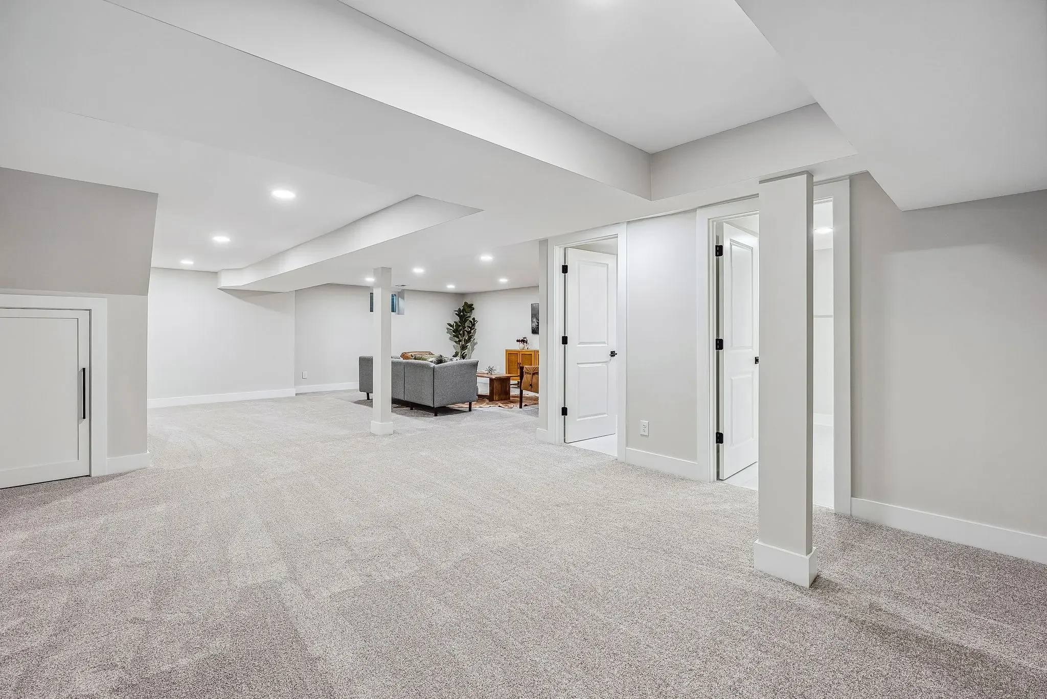 Finished basement remodeling in Columbus, Ohio featuring open-concept lower-level living space, recessed lighting, upgraded carpet flooring, custom utility room doors, and modern basement finishing by Elevate Remodeling.