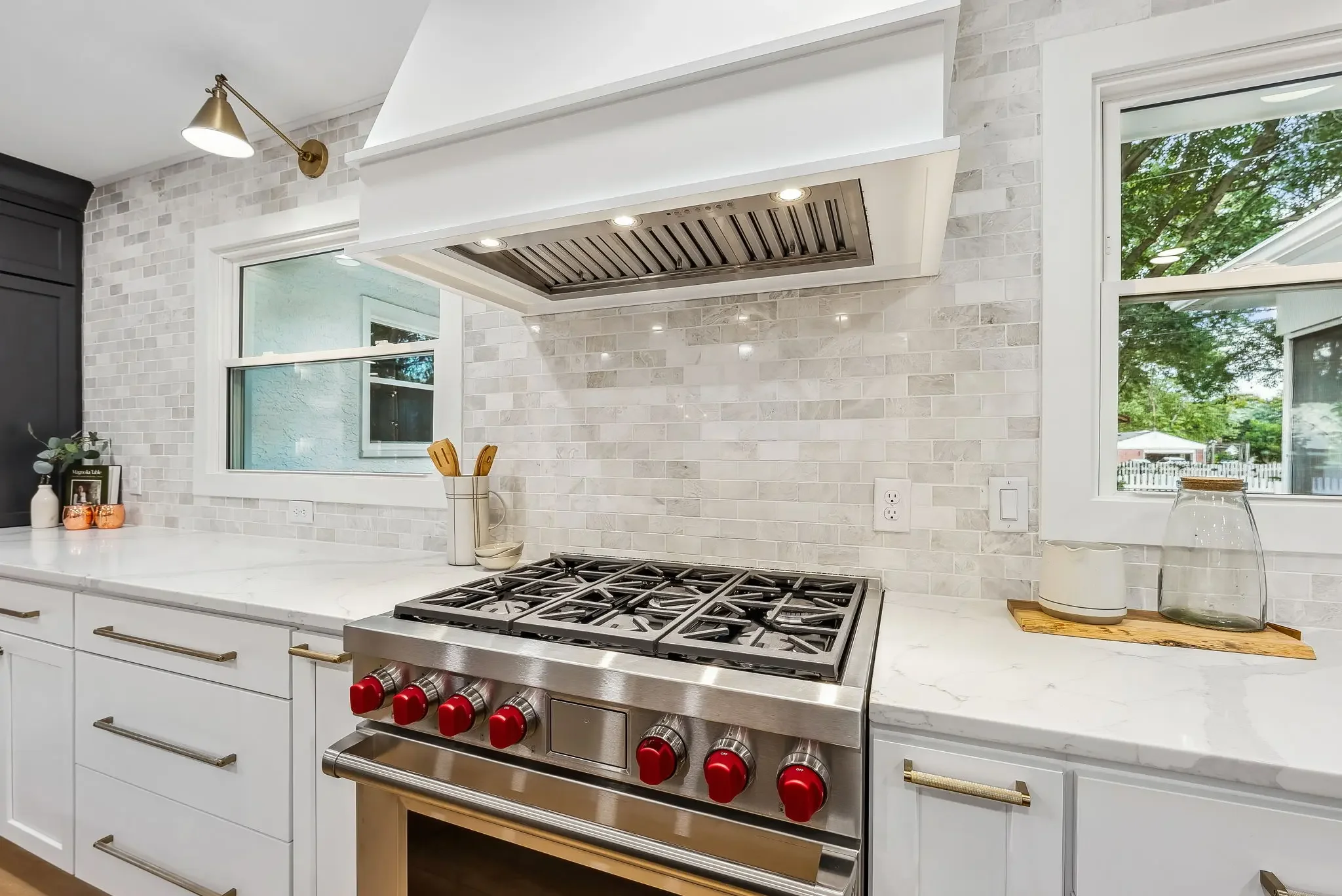 Custom Columbus kitchen remodel featuring professional gas range, plaster hood vent, stone backsplash, and brass sconces