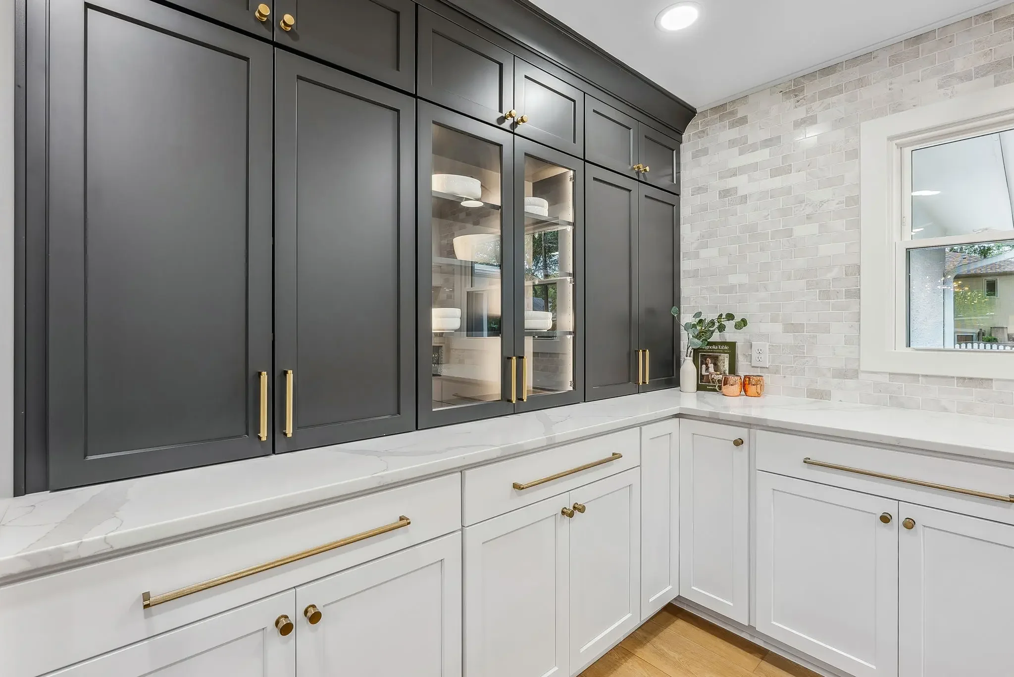 Kitchen remodeling in Columbus, Ohio featuring custom cabinetry, quartz countertops, brass cabinet hardware, glass-front storage, and modern transitional kitchen design by Elevate Remodeling.