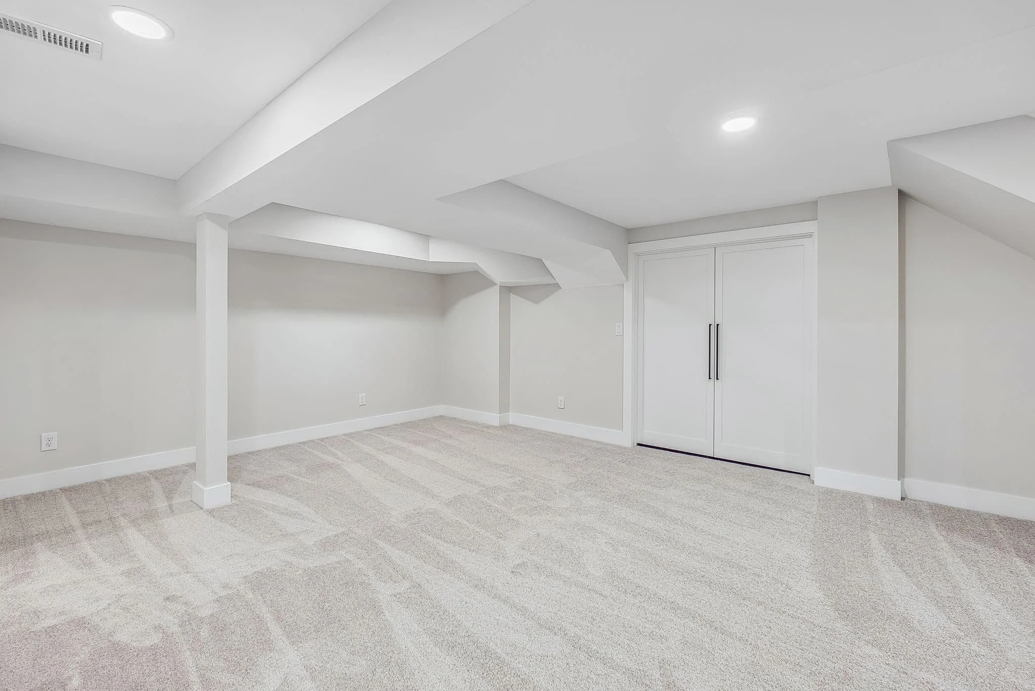 Finished basement in Upper Arlington, Ohio featuring custom utility room doors, recessed lighting, upgraded carpet flooring, integrated storage solutions, and lower-level renovation by Elevate Remodeling.