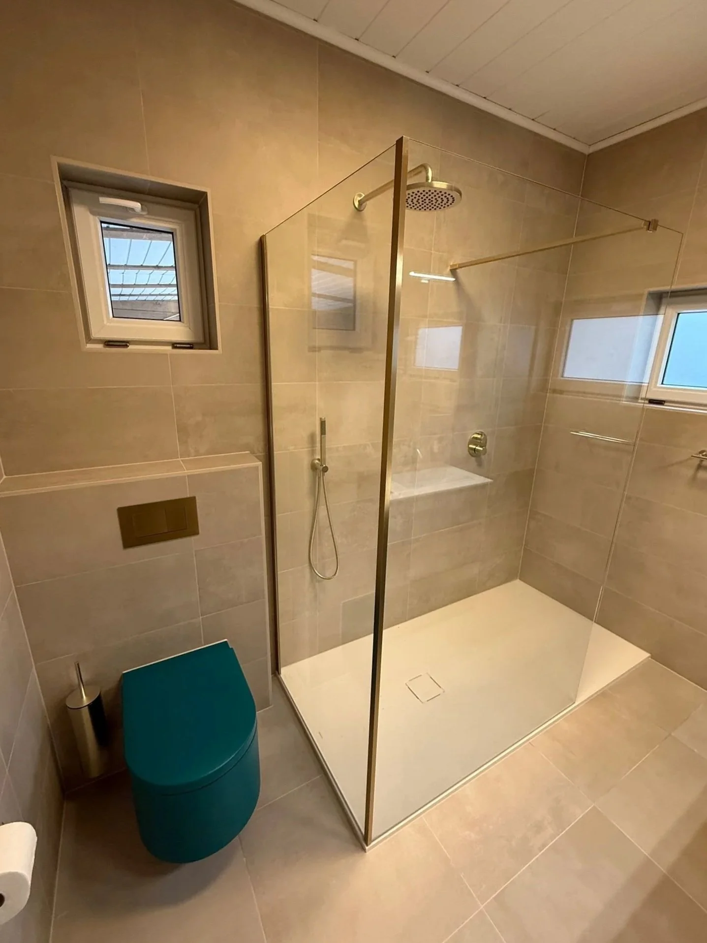 Moderne badkamer met inloopdouche, toilet en kleine ramen voor natuurlijk licht