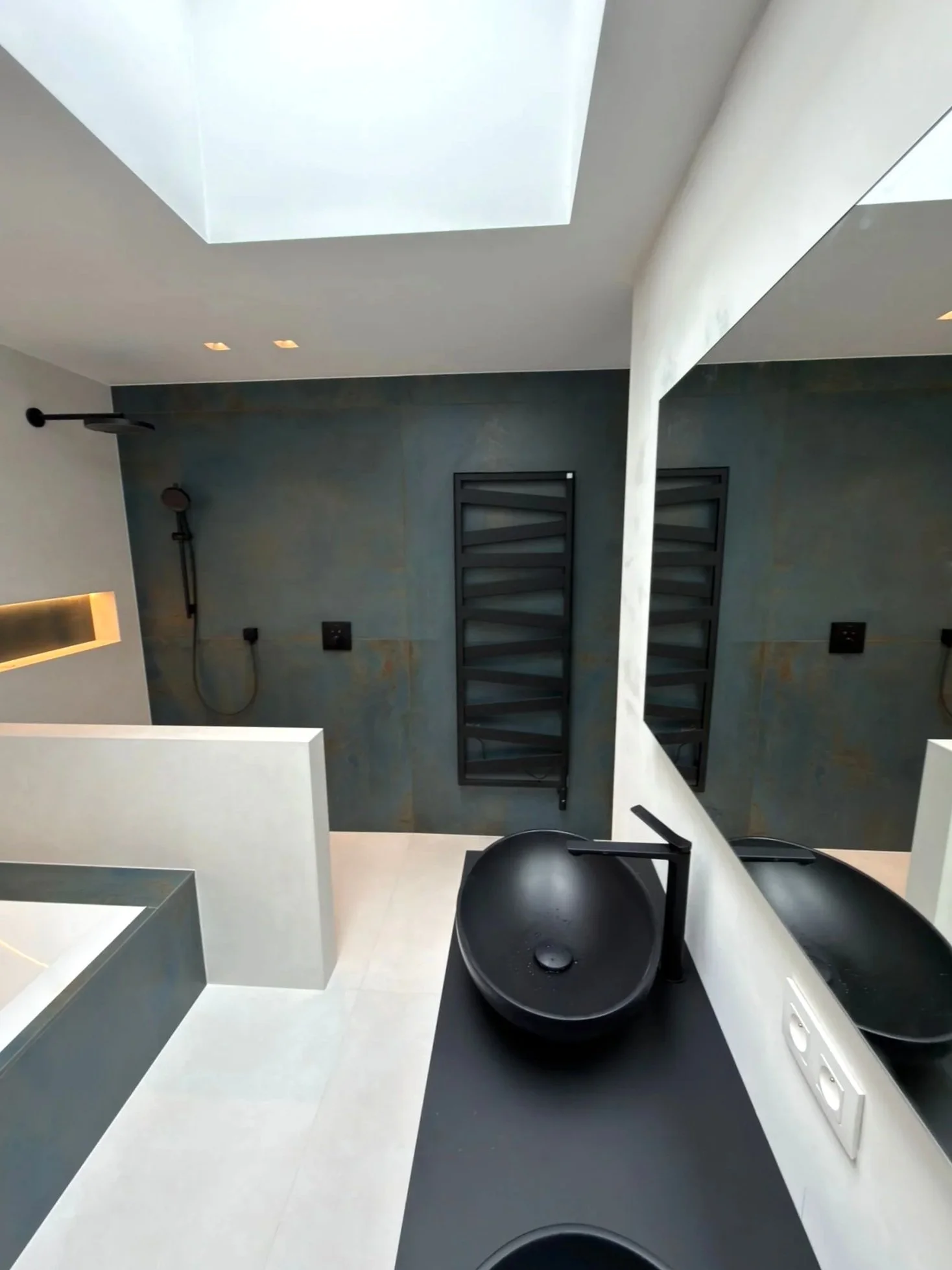 Moderne badkamer met zwart-wit accenten. Moderne radiator, opzetwaskommen en zwart kraanwerk.