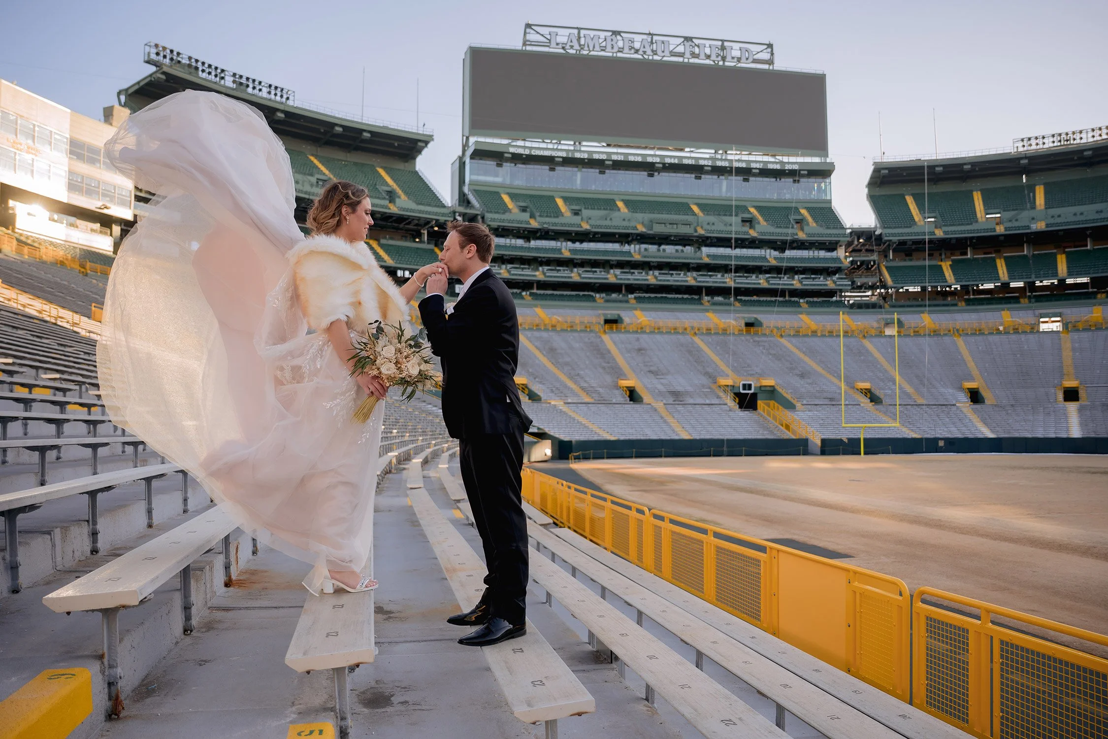 0010reminisce-milwaukee-wi-photographer-lambeau-field-bride-groom-kissing-hand-train-blowing.jpg