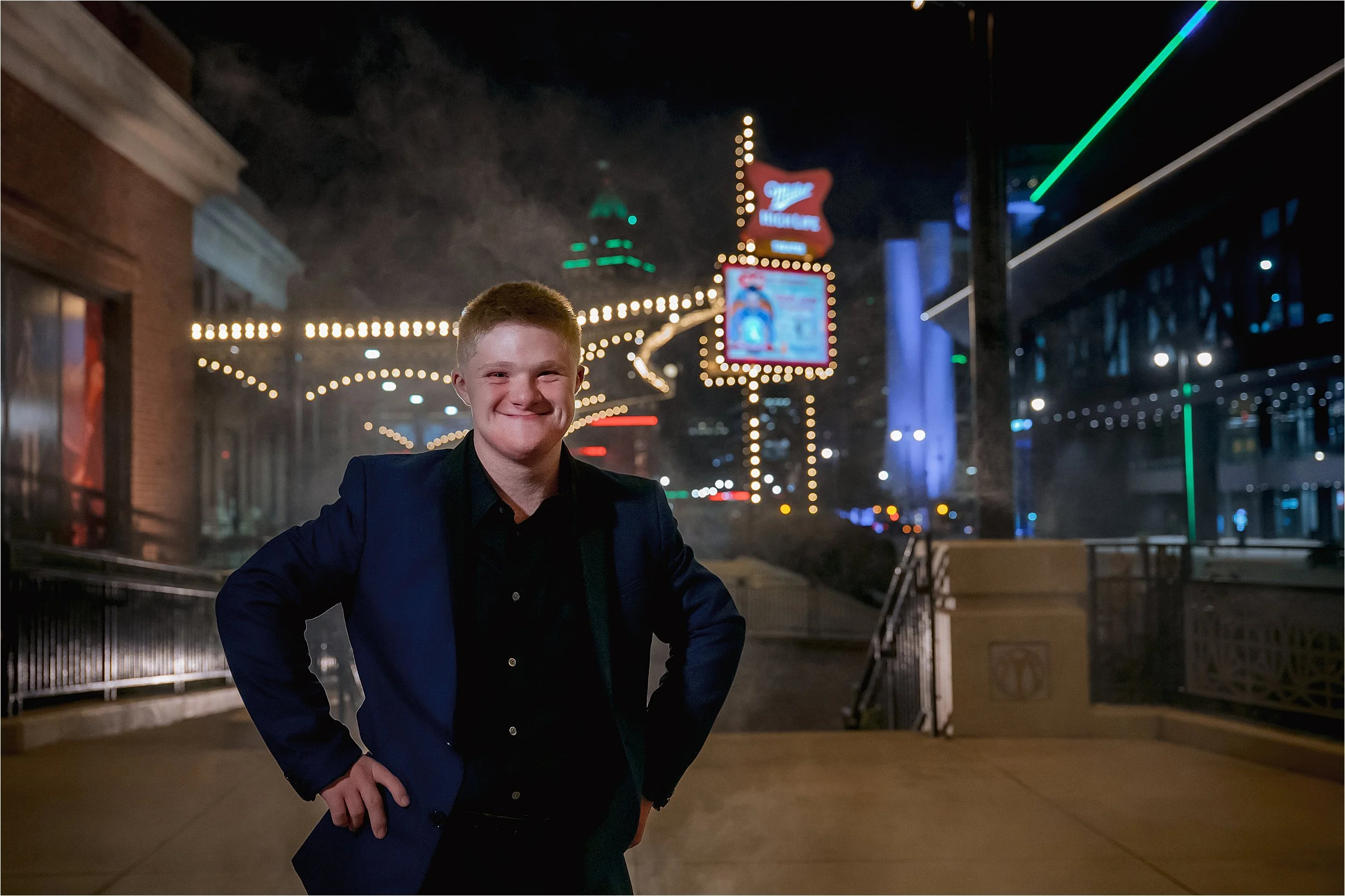 Nighttime downtown Milwaukee senior portrait with glowing theater lights and fog