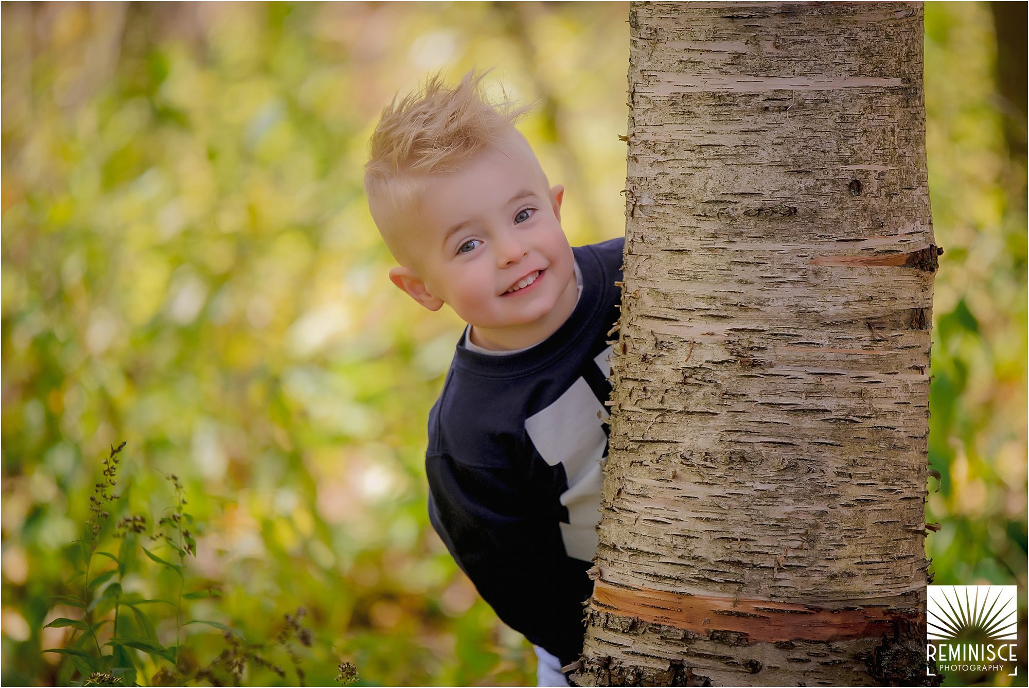 12-third-birthday-portraits-fall-photos-schlitz-audubon-nature-center-playing-peek-a-boo-behind-tree.jpg