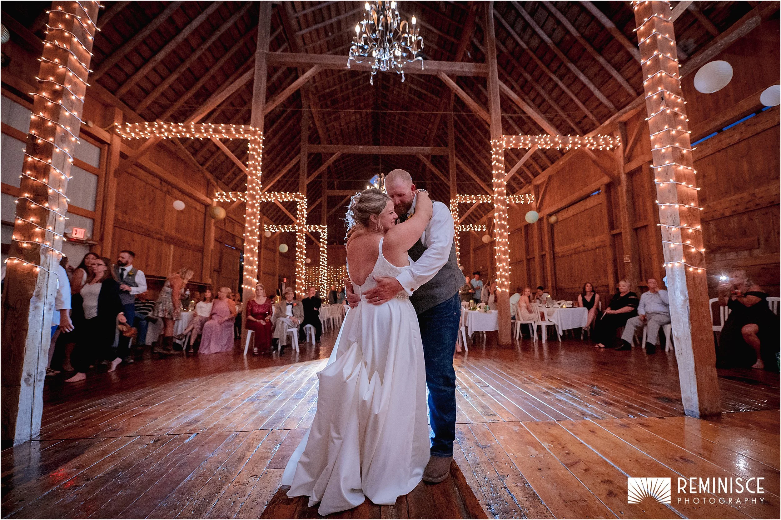 22-bride-groom-dancing-under-chandelier-barn-wrapped-twinkle-lights-beams.JPG