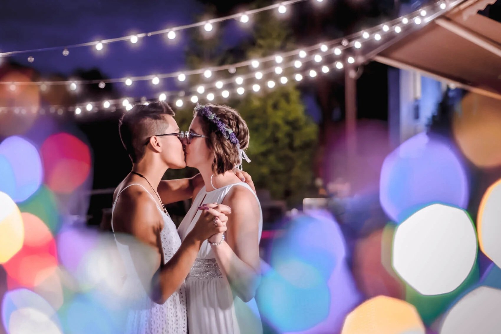 077-lgbt-friendly-photography-brides-kissing-colorful-light-bokah.jpg