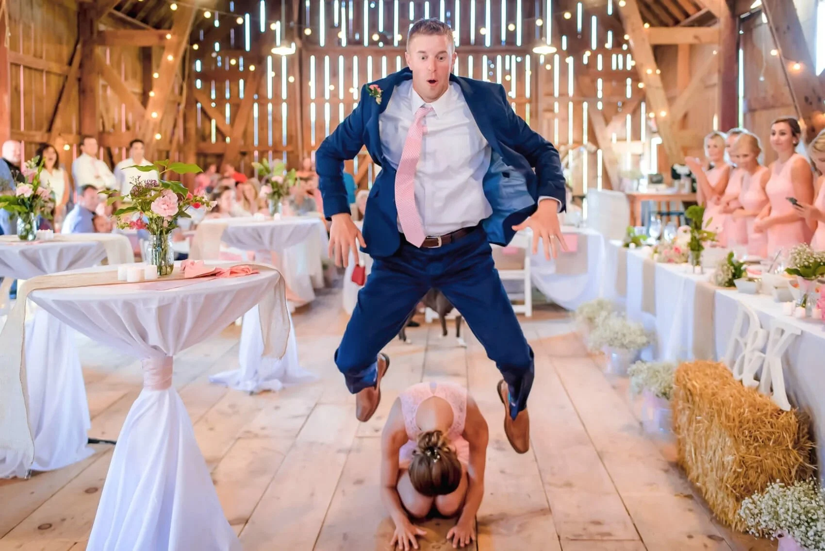 34-wisconsin-barn-wedding-reception-photography-groomsman-jumping-over-bridesmaid.jpg