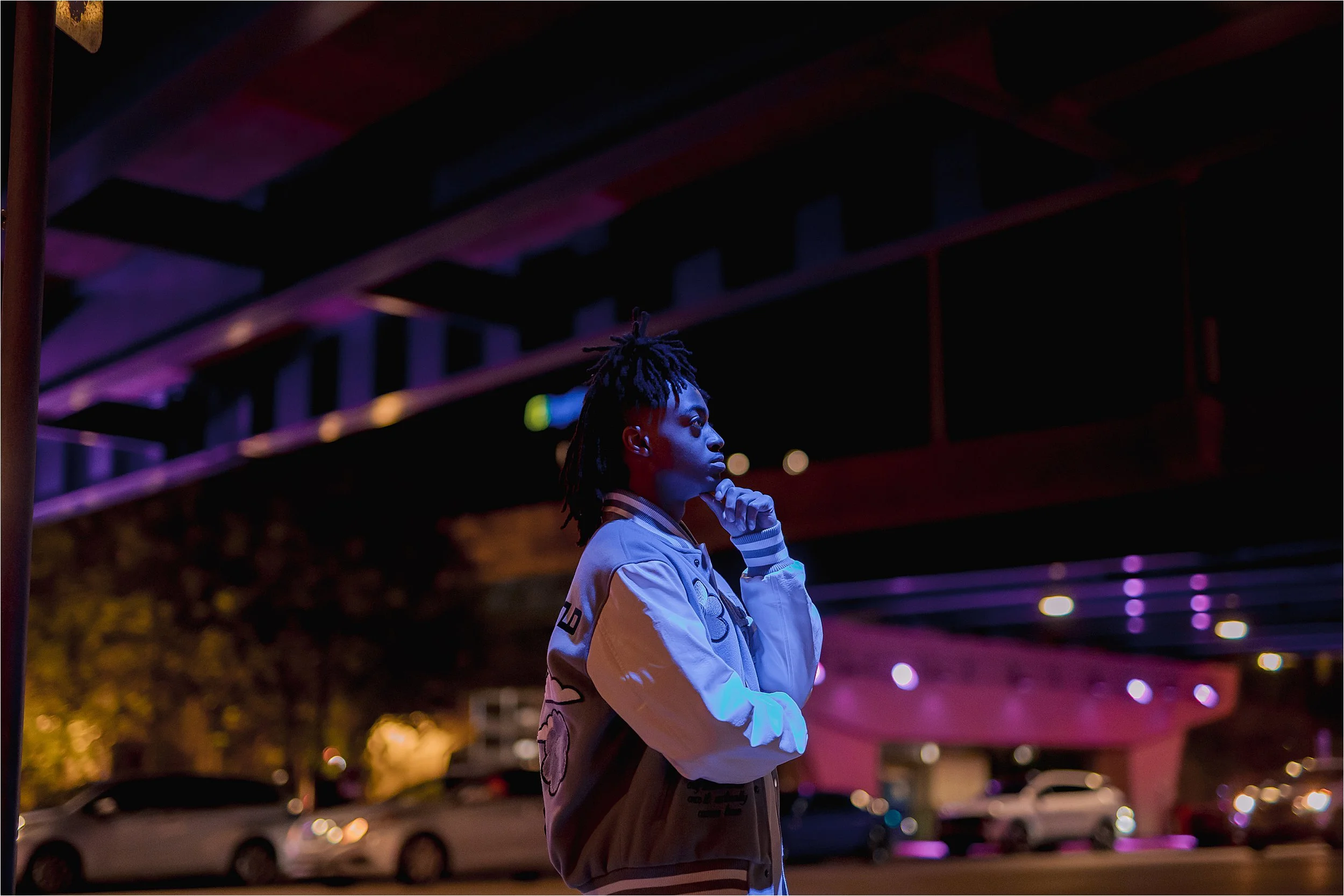 Creative nighttime senior portrait in Milwaukee with dramatic purple and blue lighting near third ward underpass