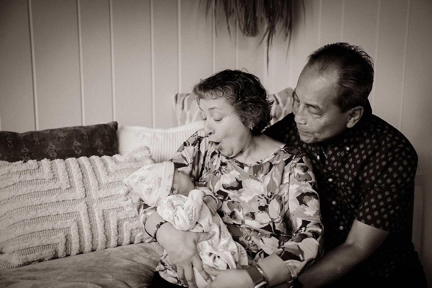 Grandparents holding their newborn grandchild during an in-home Milwaukee newborn photography session