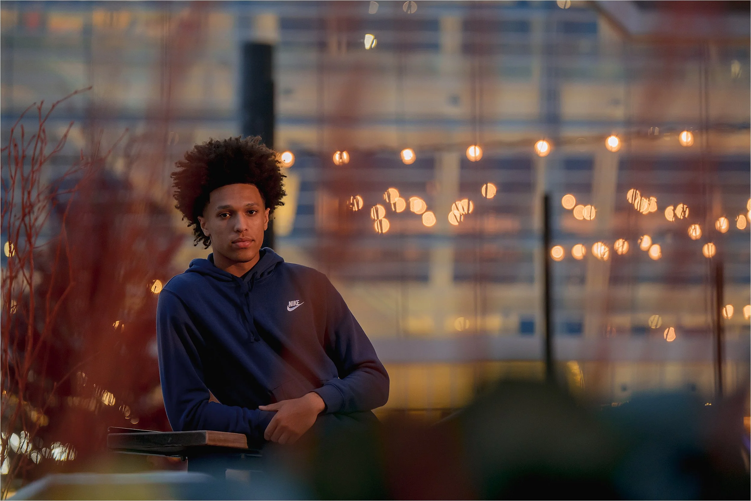 Urban senior portrait in Milwaukee with city lights and bokeh at dusk in deer district
