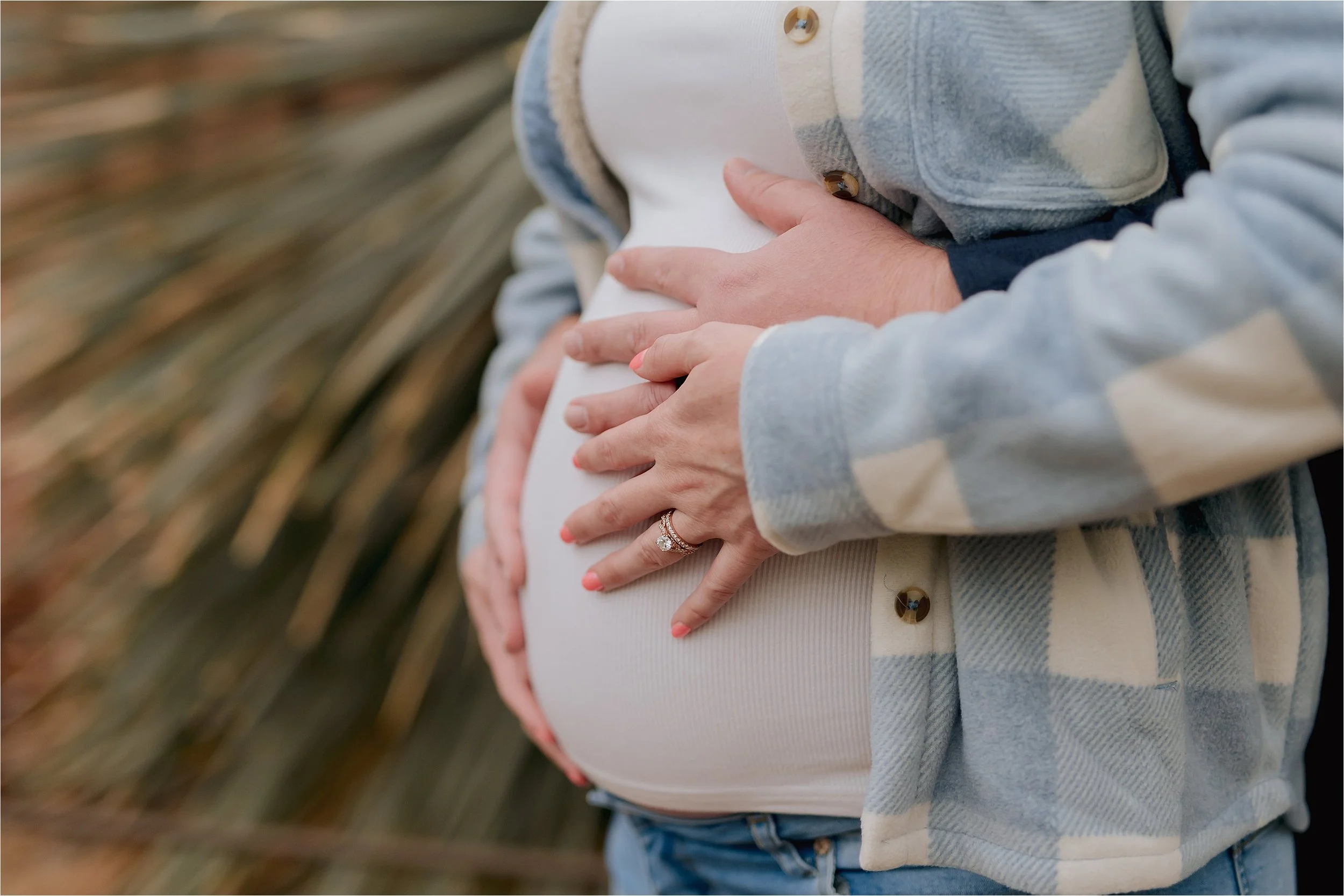 Close up of hands holding baby bump during outdoor maternity session