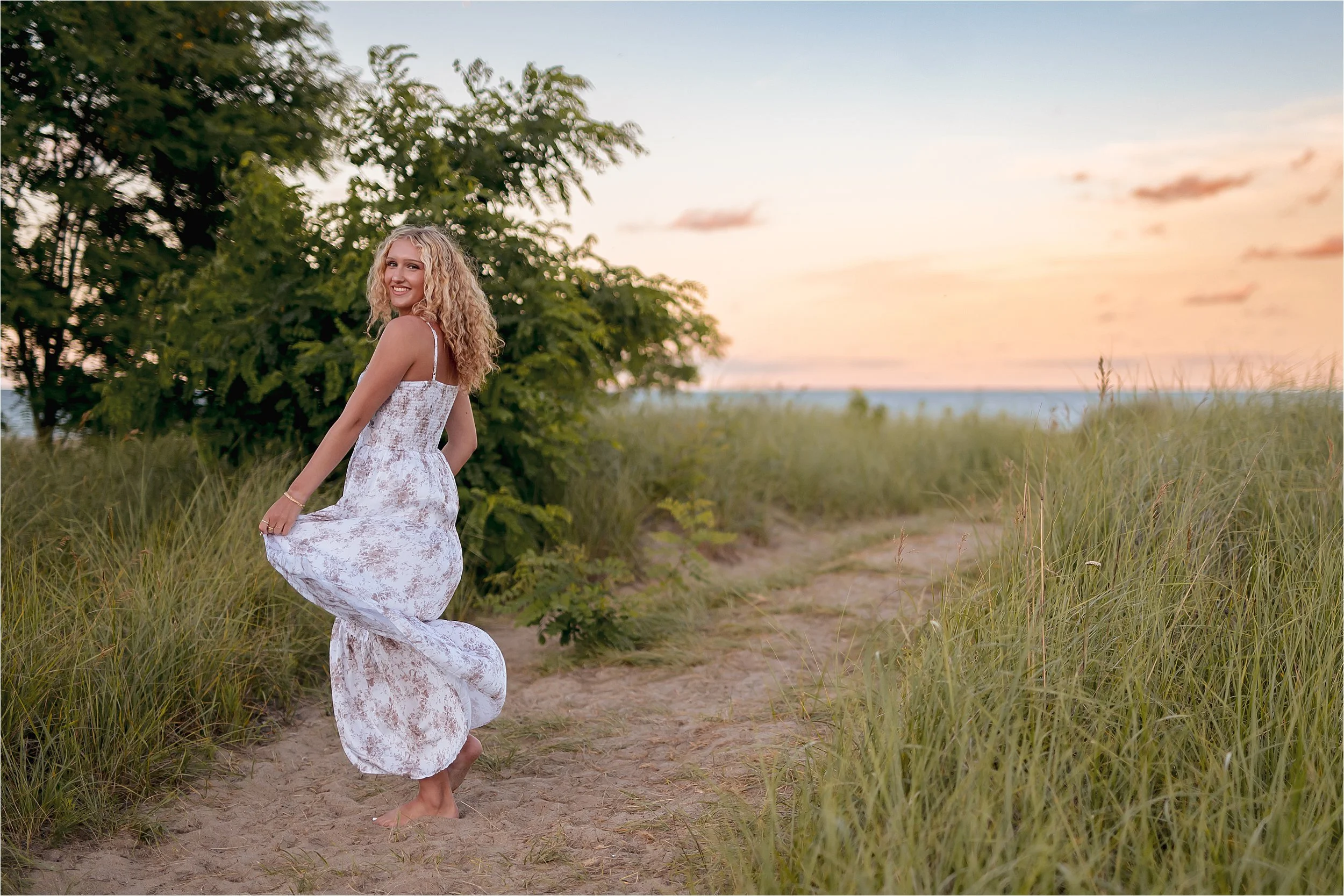Senior walking through sandy dunes at sunset during a Milwaukee beach senior picture session at grant park seven bridges