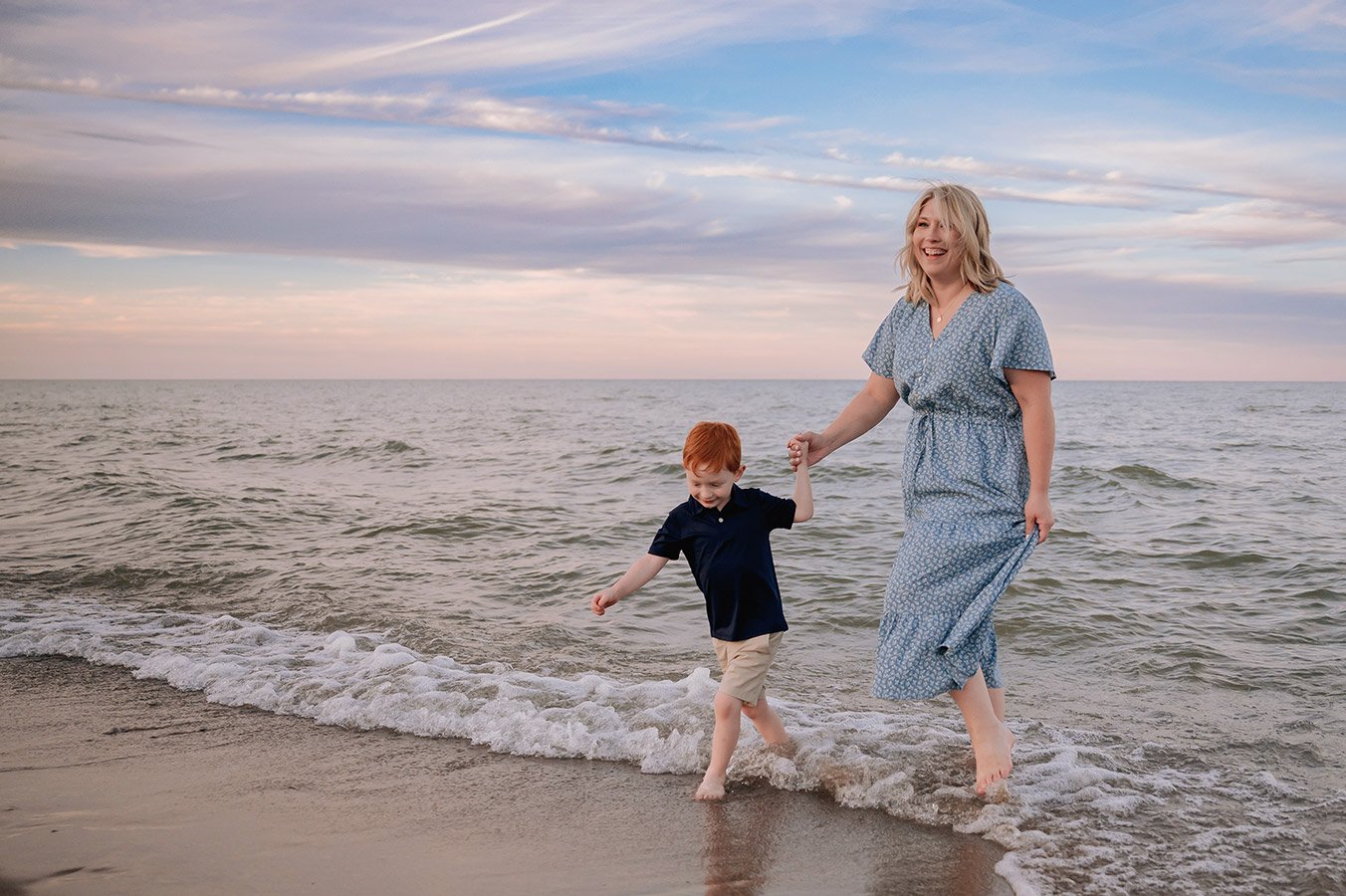 Milwaukee family photographer capturing a candid mother and son walking along Lake Michigan during a beach session at Grant Park's Seven Bridges