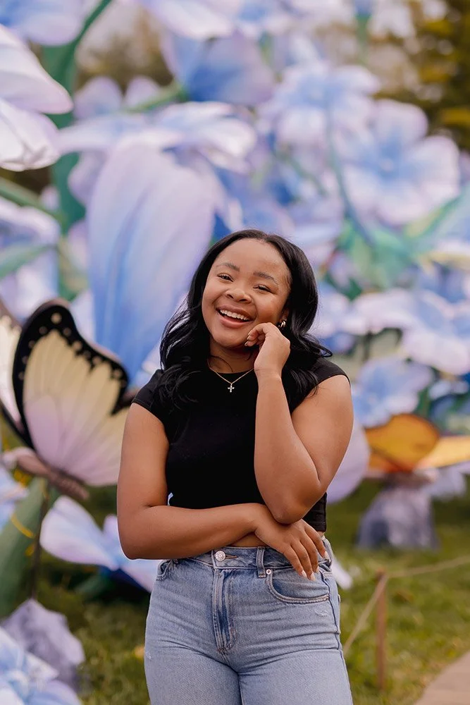 High school senior smiling in front of a colorful flowers in Milwaukee during a creative senior portrait session at Boerner Botanical Gardens