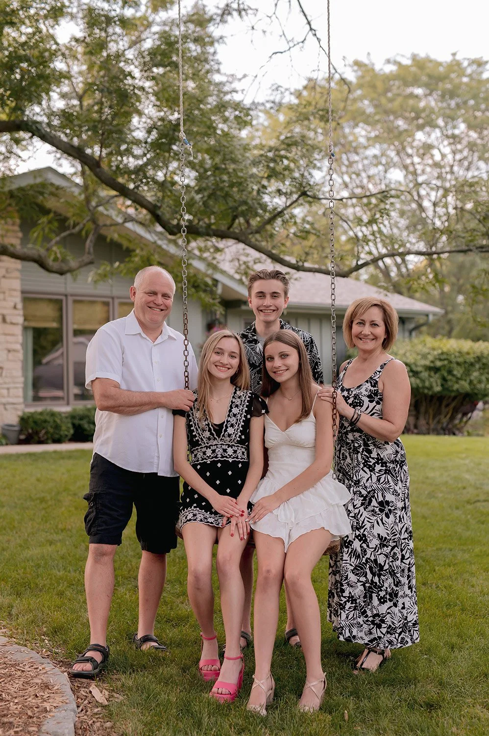 Posed family portrait photographed outdoors by a Milwaukee family photographer during a relaxed summer session with a tree swing in backyard