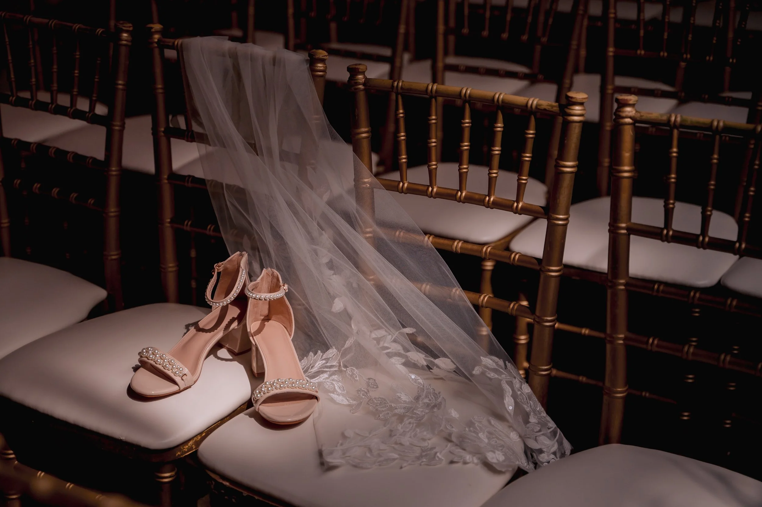 Bride’s shoes and veil arranged on ceremony chairs