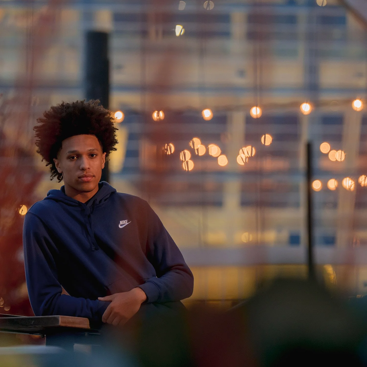 High school senior posing in an urban Milwaukee setting with warm city lights in the background during an evening portrait session