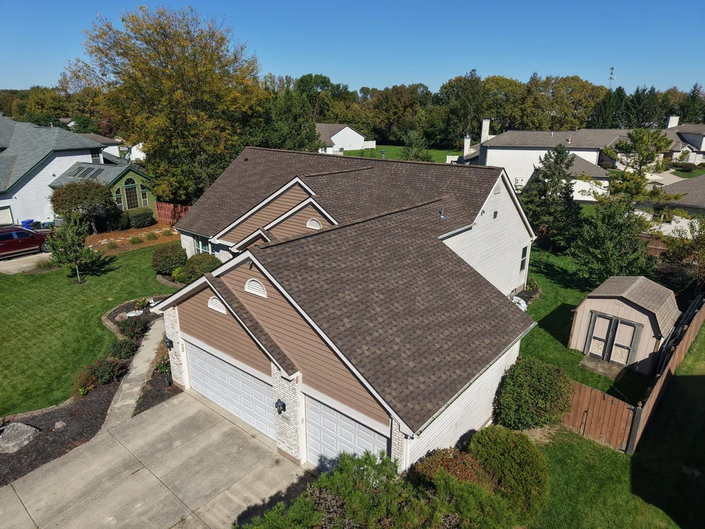 Aerial view of a completed brown shingle roof on a home with a white garage door in Central Ohio