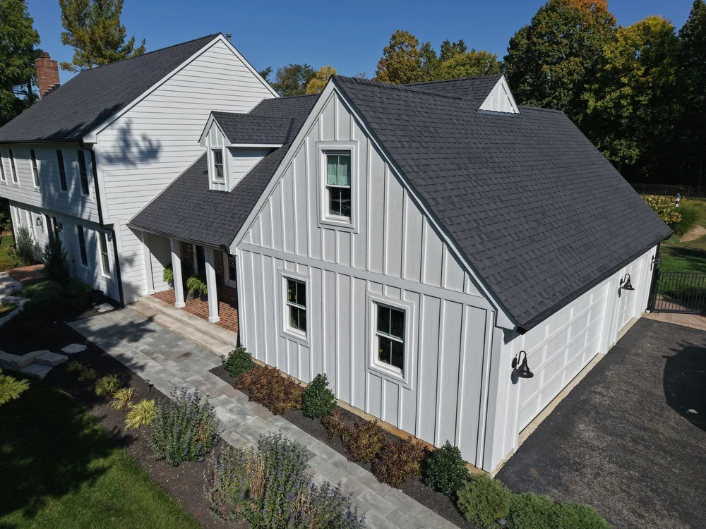 Freshly installed charcoal shingle roof on a white board-and-batten home in Central Ohio