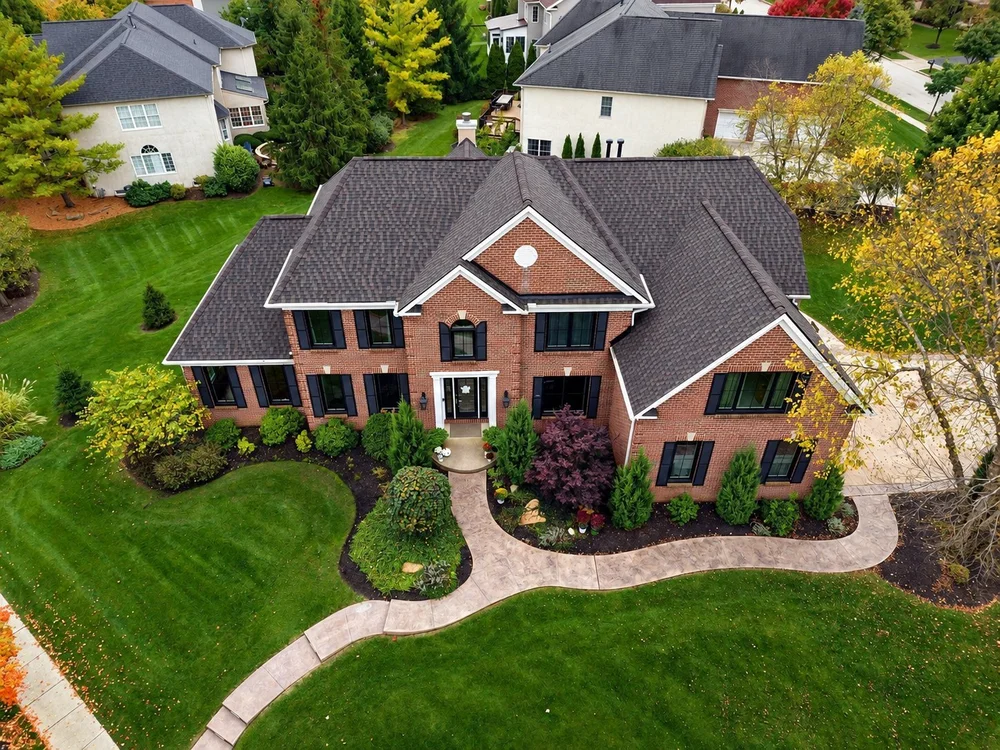 Aerial view of a brick home with a dark shingle roof