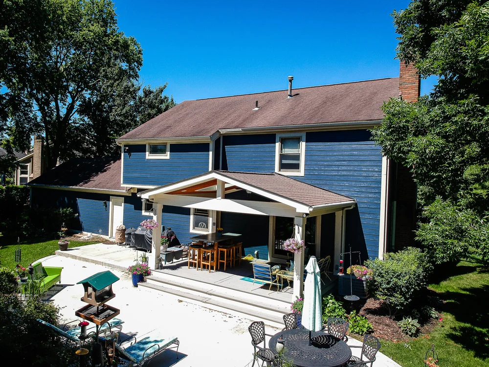 Blue siding home with covered patio and landscaped yard, completed by RoofNut