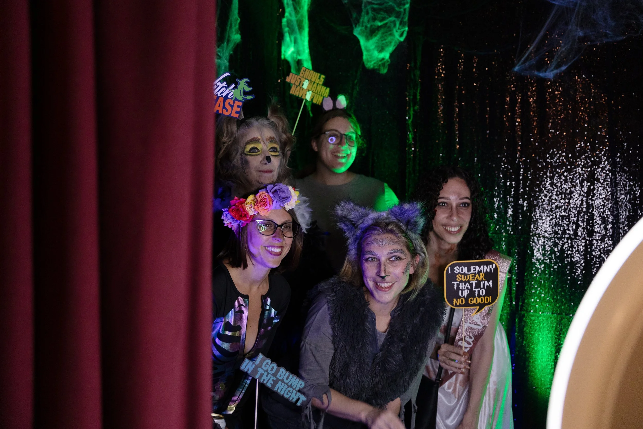 A group poses with a photobooth. They are dressed in fun Halloween costumes.