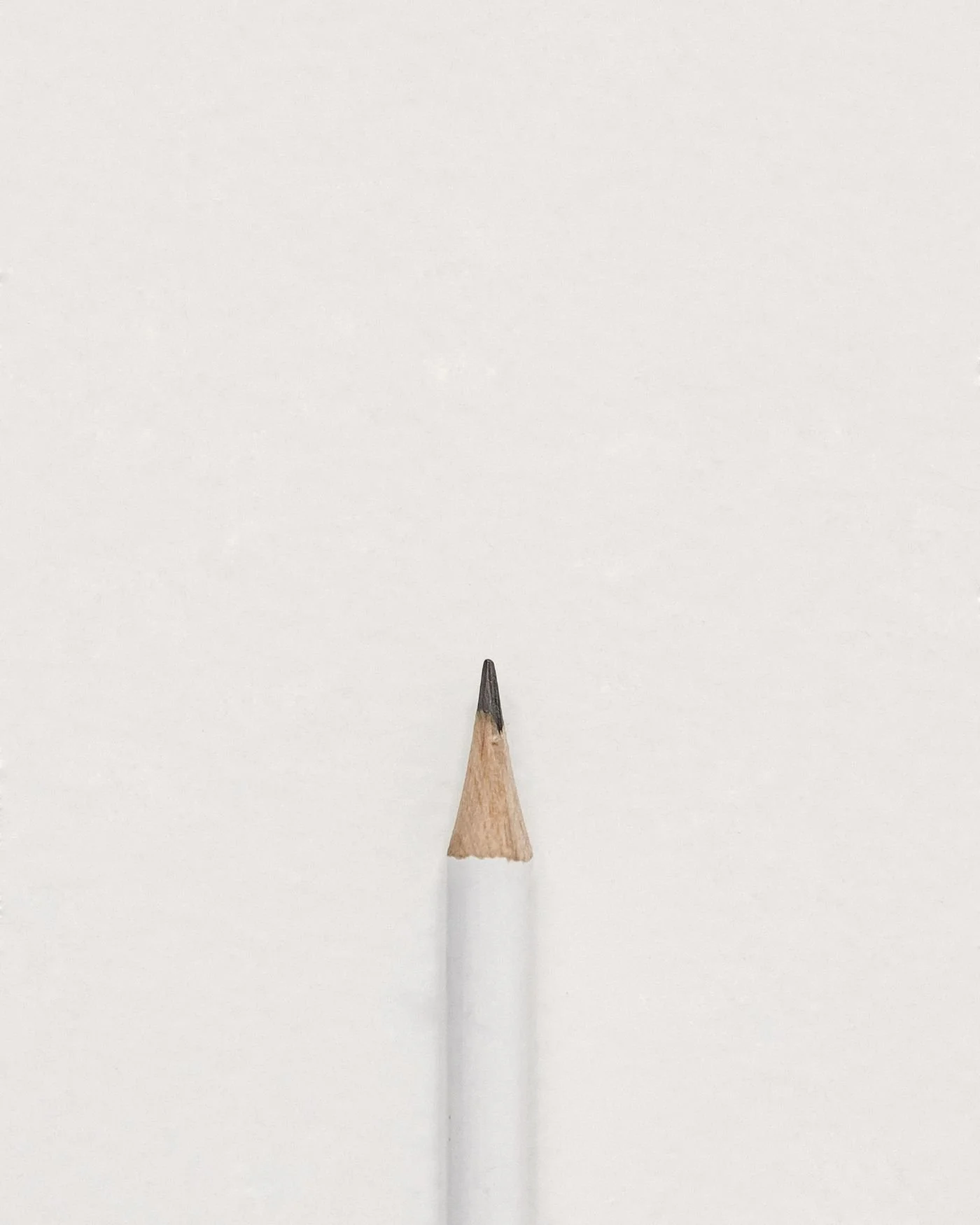 Close-up of the tip of a sharpened wooden pencil against a plain white background.