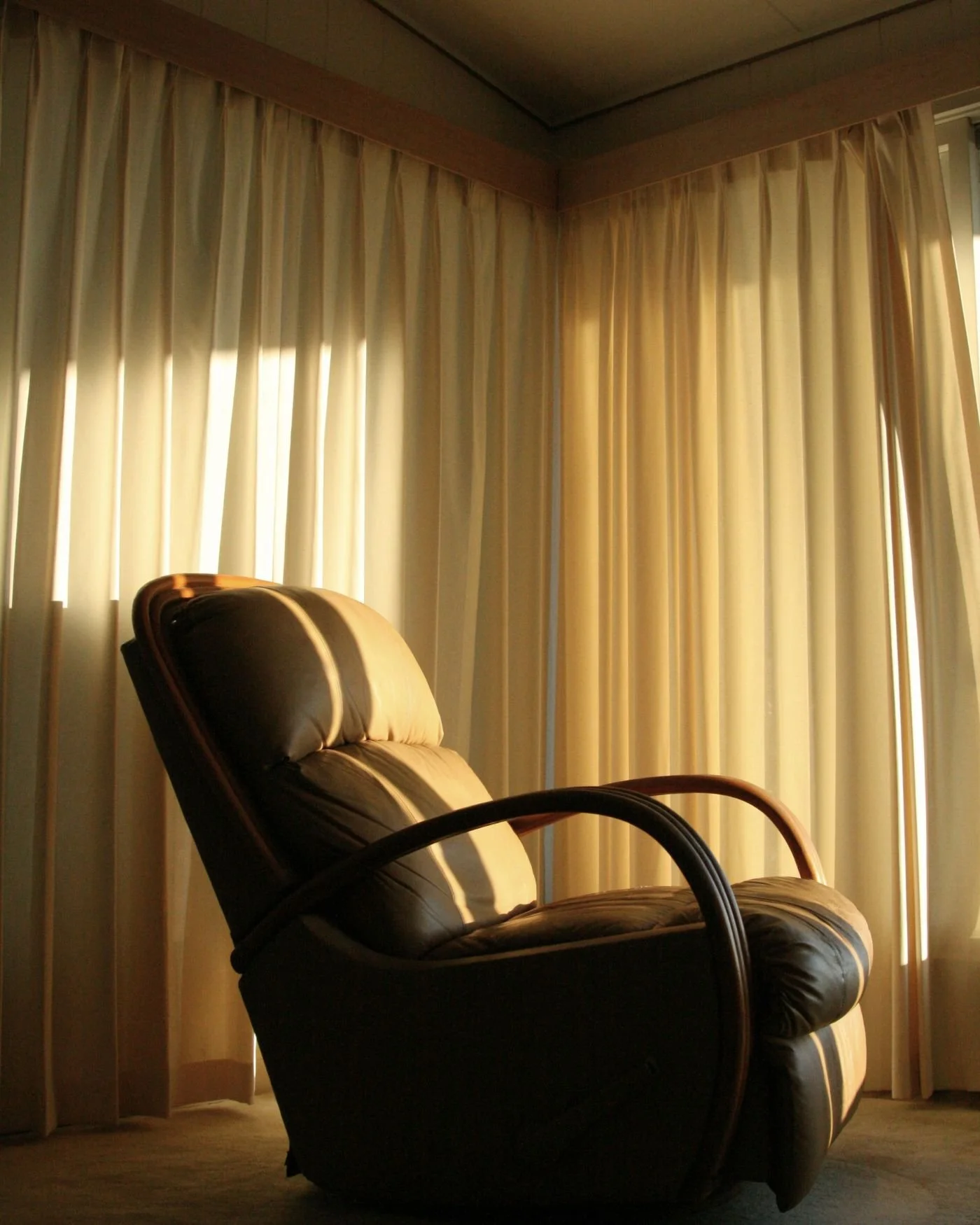 Ann empty leather armchair softly lit by light through the window.