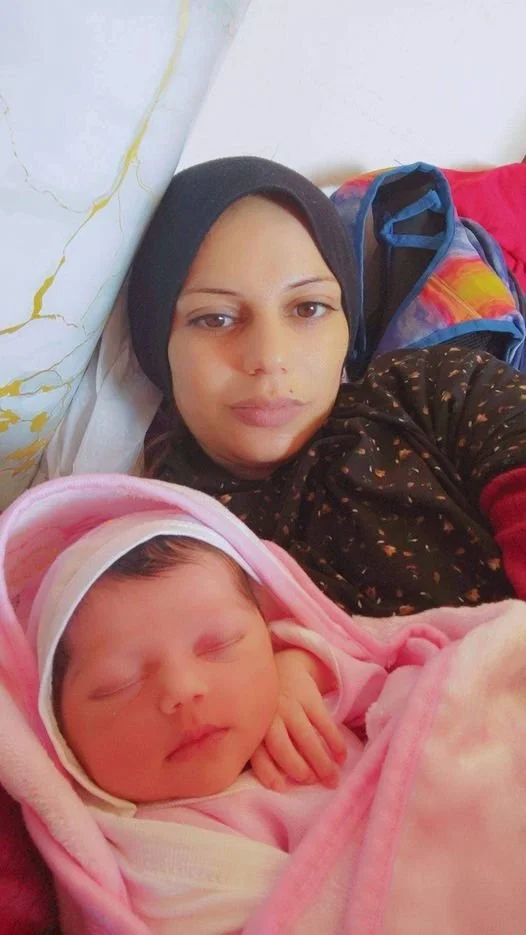 Woman and newborn baby wrapped in pink blanket, lying together.