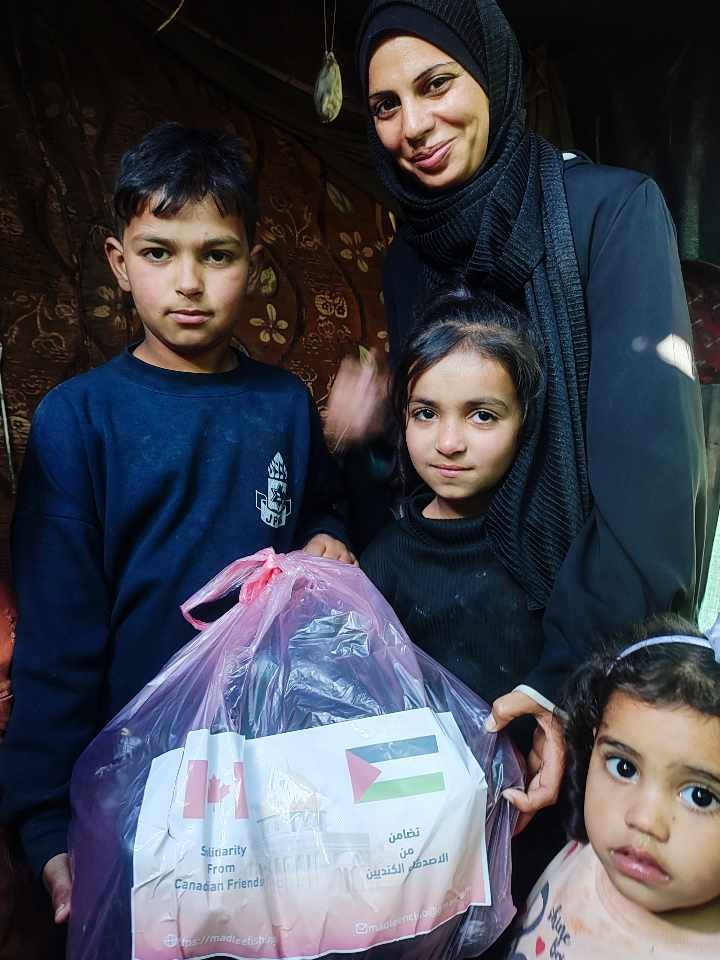A woman and three children holding a bag with flags and text, indicating support from Canadian friends.